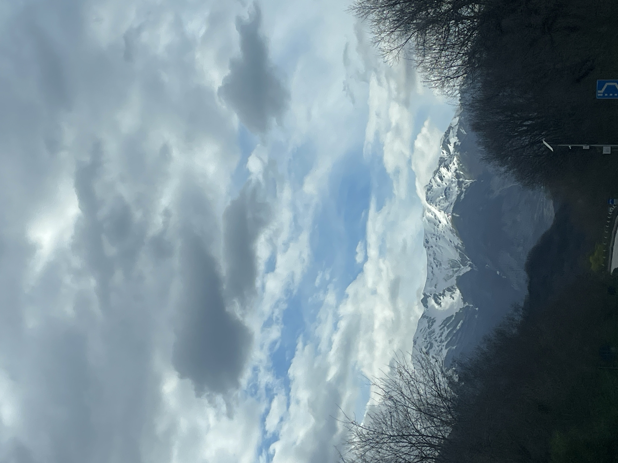 Snow-capped mountains photographed from vehicle in Italian countryside