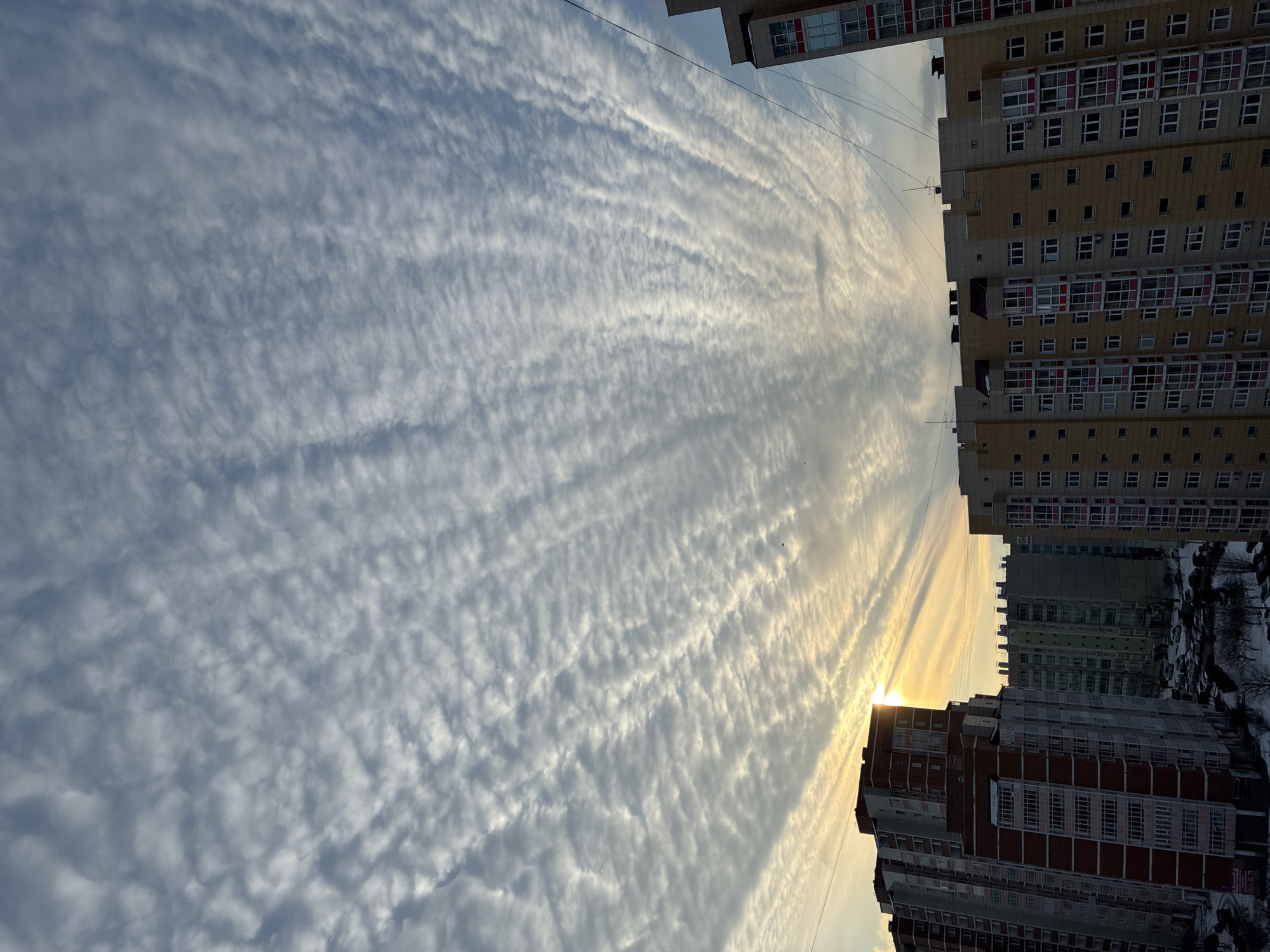 Urban skyview between apartment buildings shows striated clouds overhead