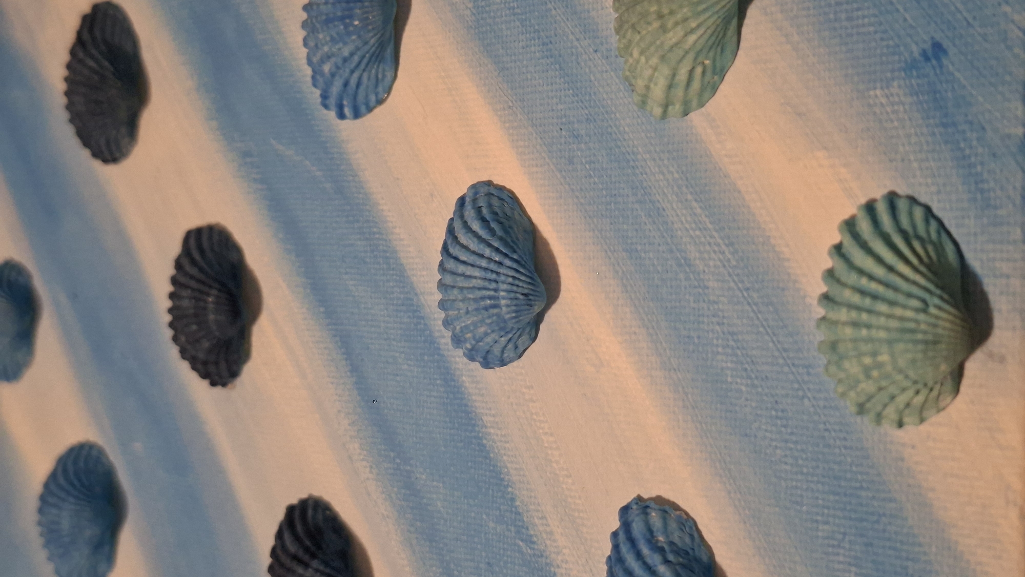 Seashell art in progress on striped canvas, Podgorica