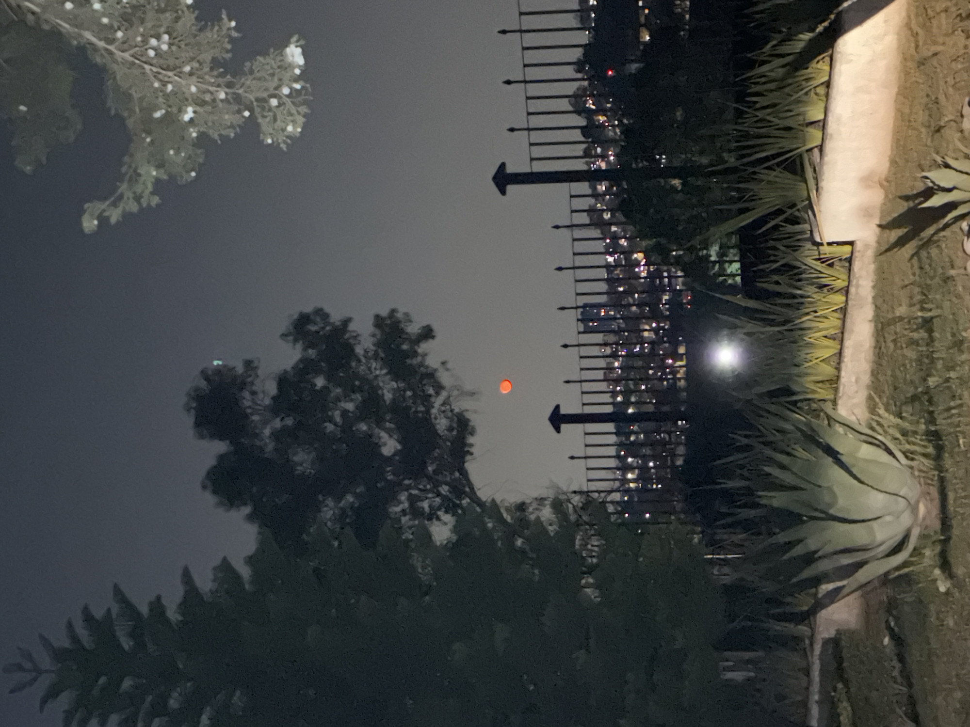 Red celestial object observed through clouds in Mexican suburb