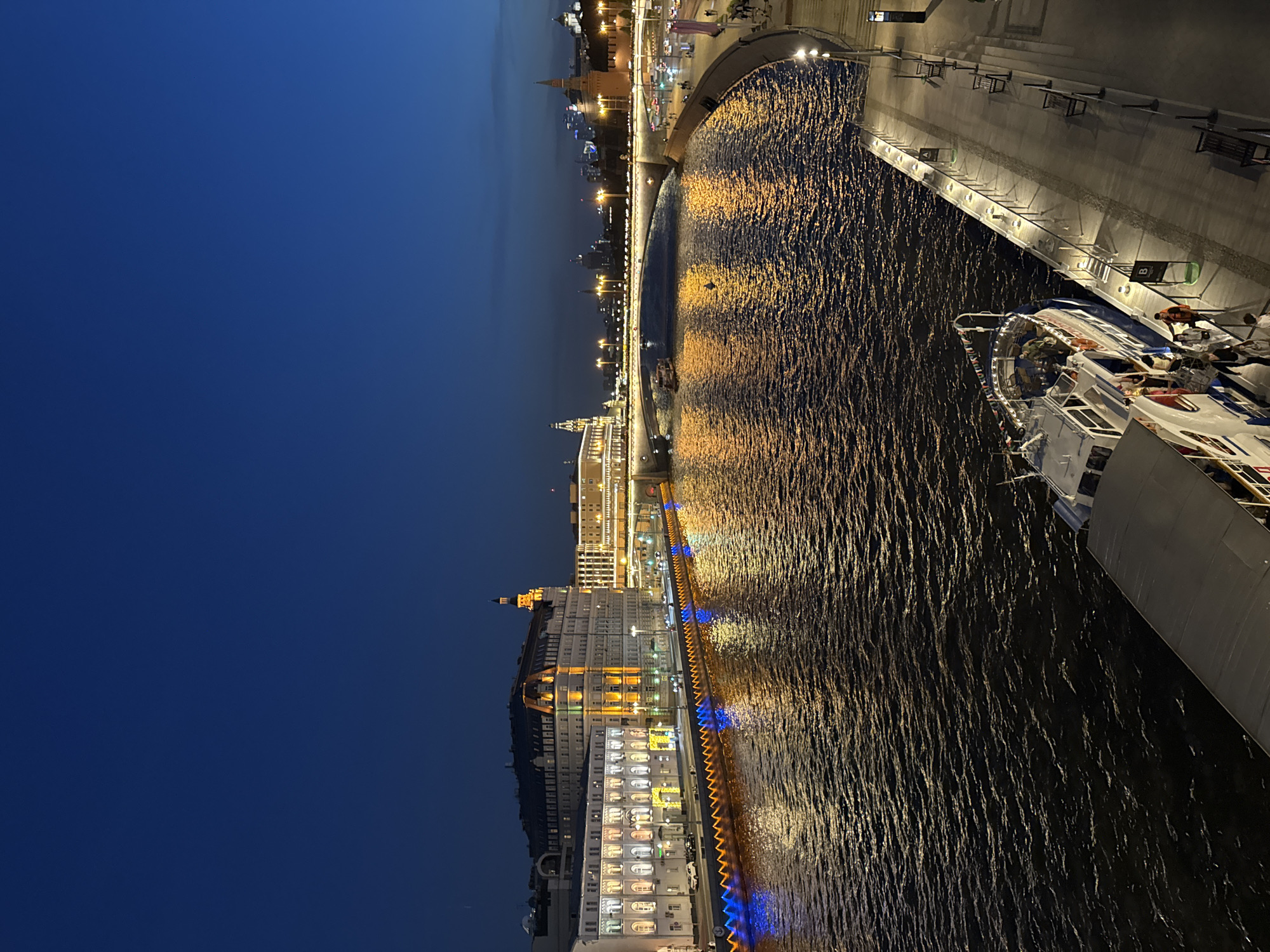 Evening cityscape observed along Moscow River featuring illuminated Stalinist architecture