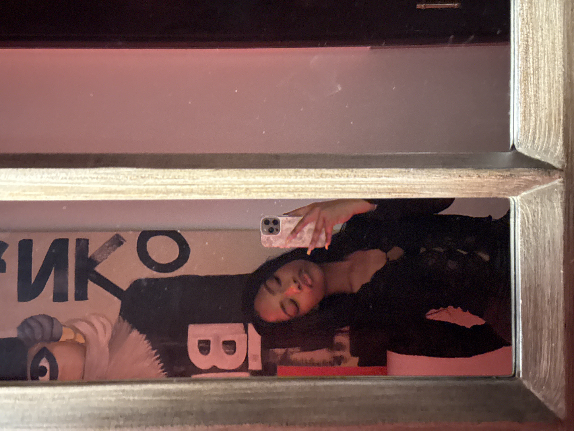 Woman Takes Mirror Selfie Near Cyrillic Poster in Moscow