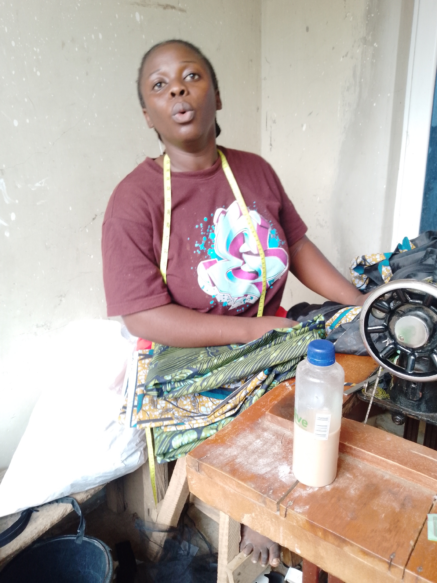 At the sewing machine, fabric and focus in a small workshop
