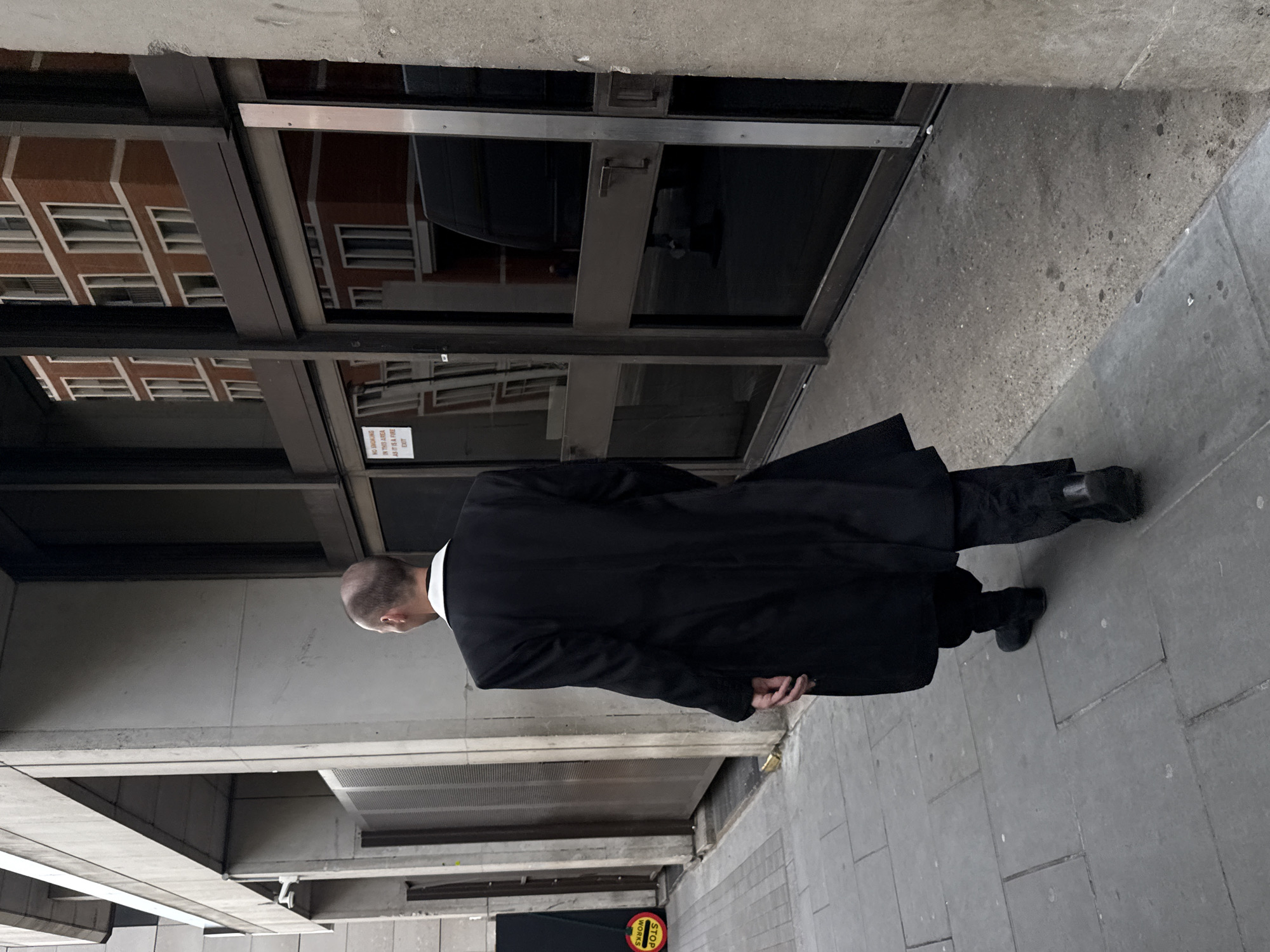 Man in black suit walks past London building