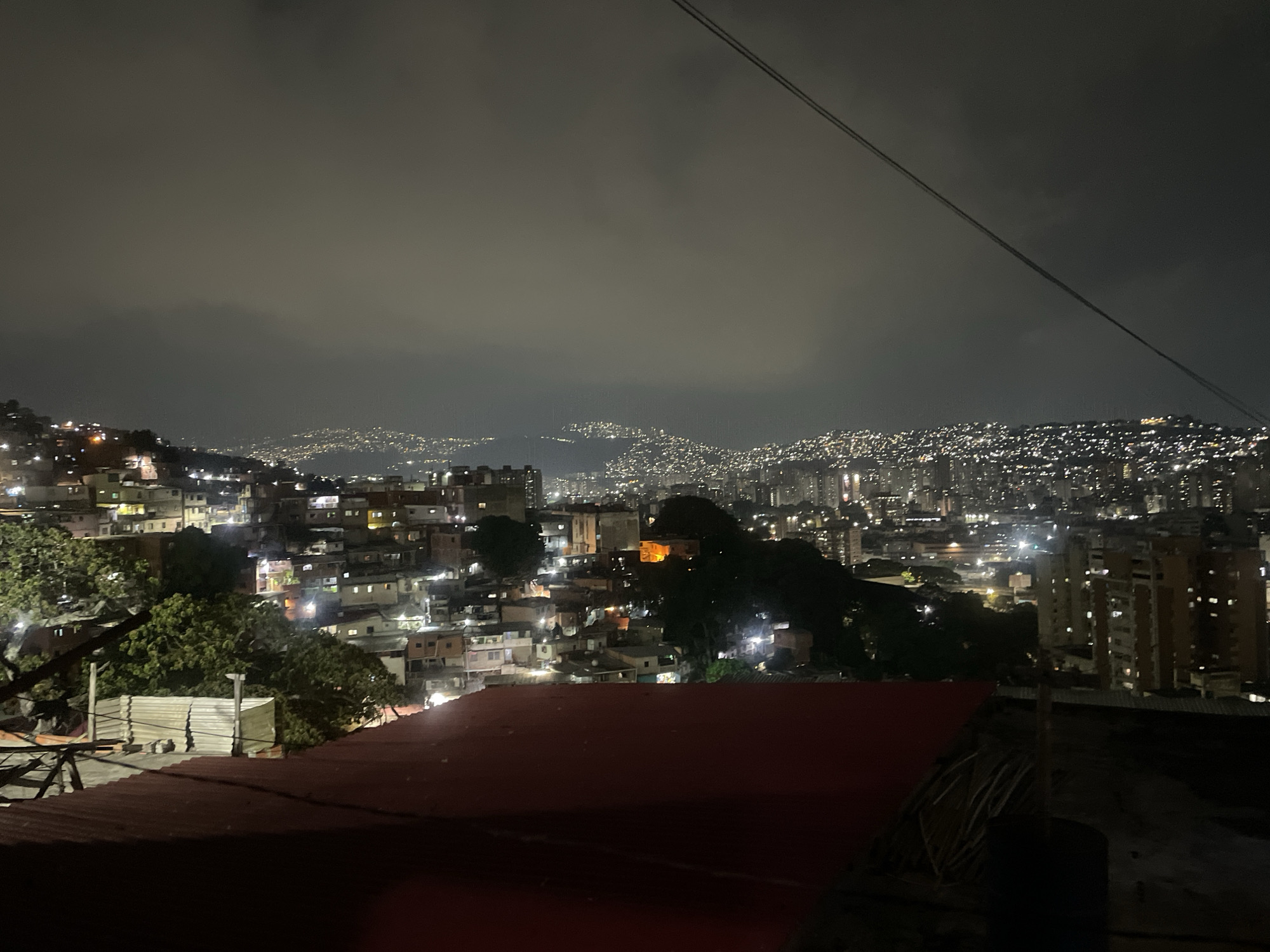 Nighttime view captures Caracas hillside housing under cloudy sky