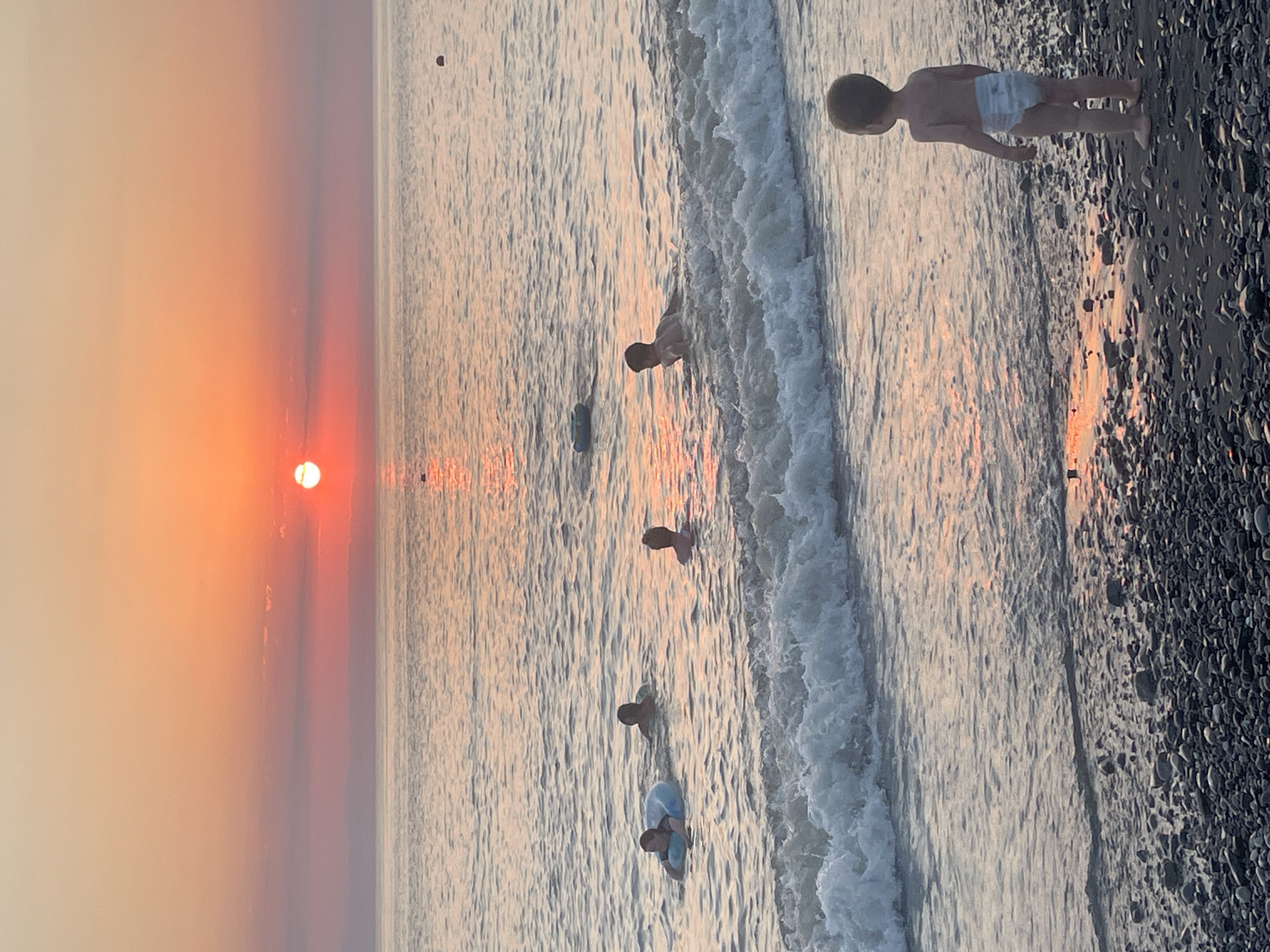 Calm beach sunset with people in the water