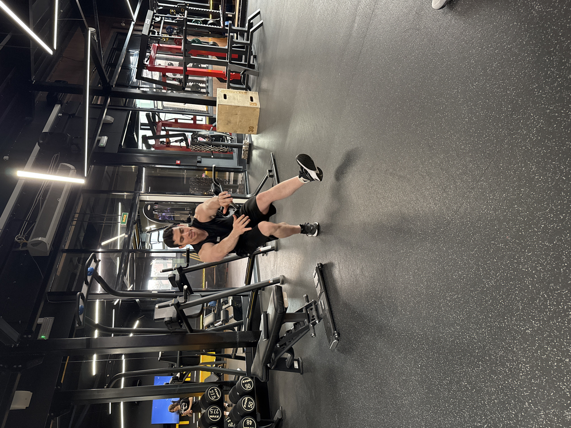 Men exercise with barbells at indoor gym facility