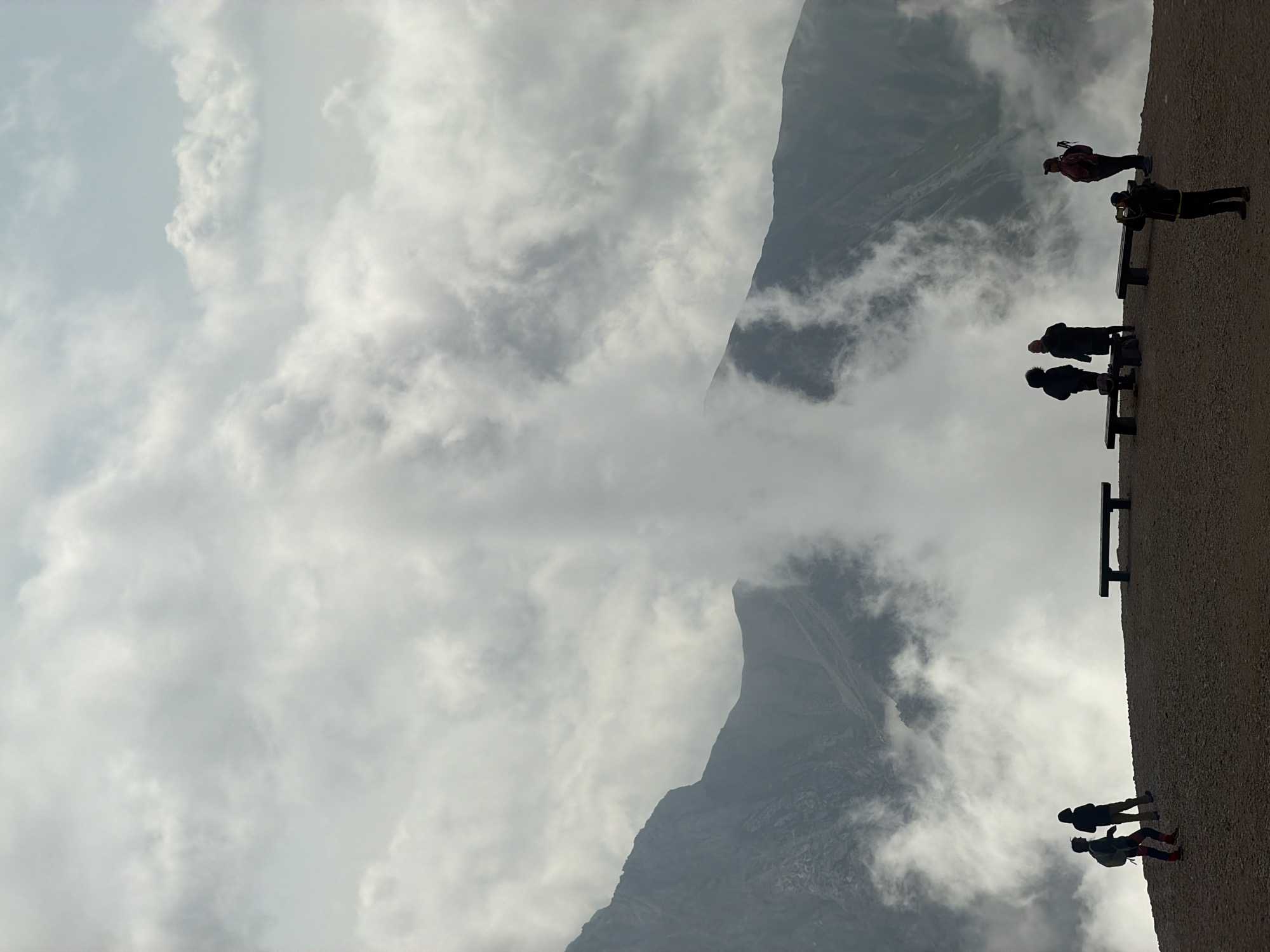 Hikers pause at a cloud-shrouded mountain overlook in Austria