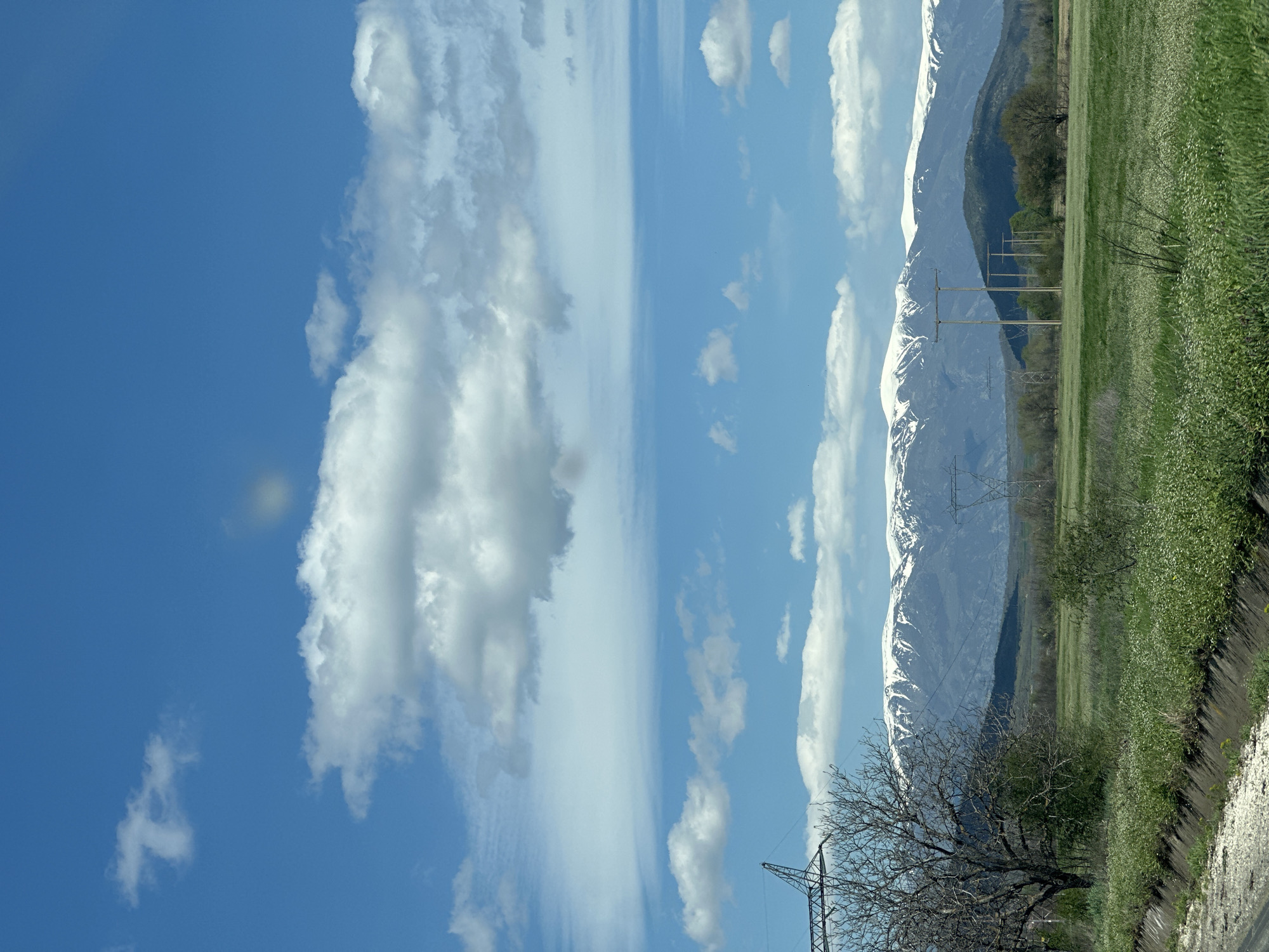 Car travels rural road near snow-capped mountains in Bulgaria