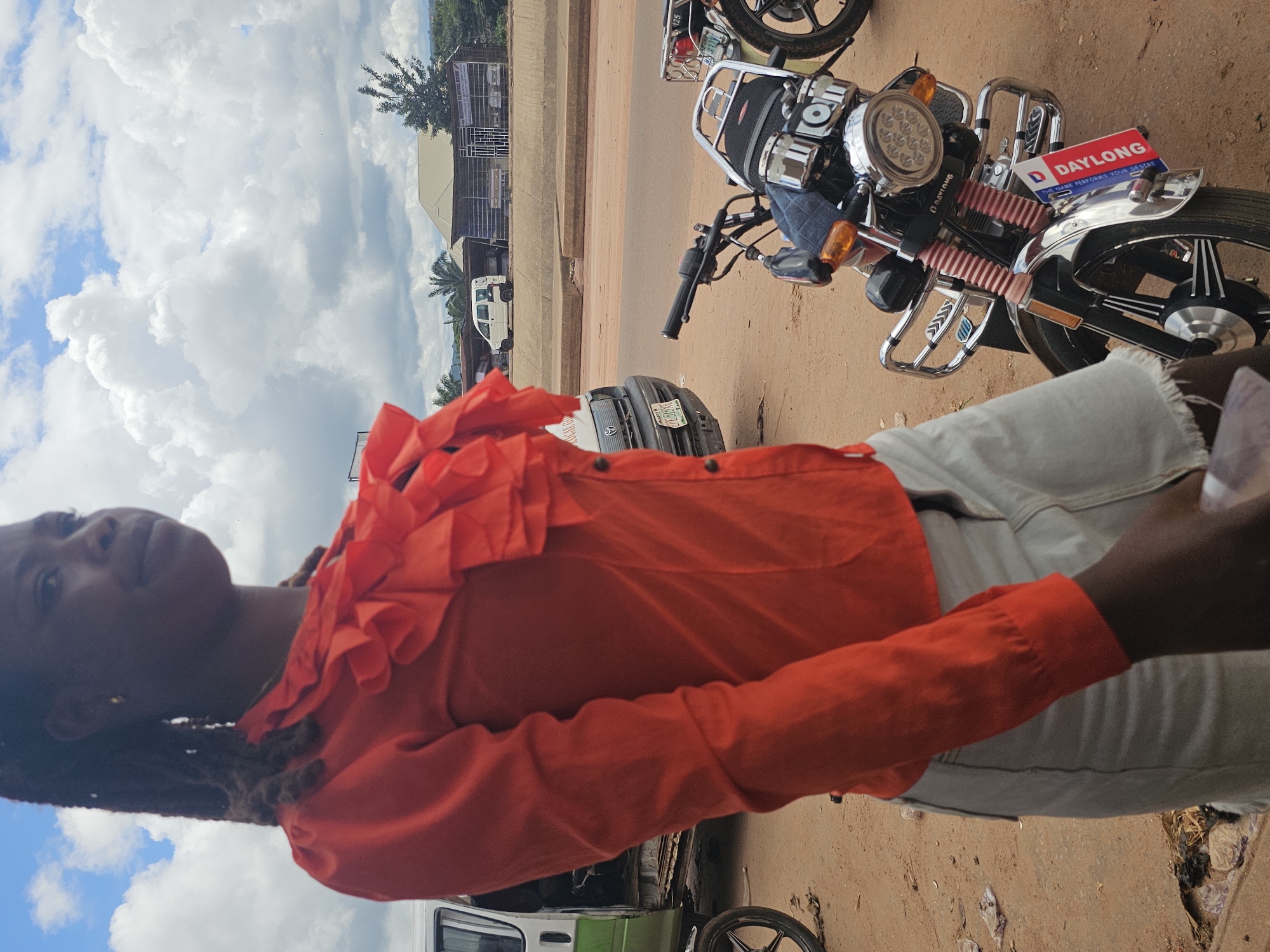 Roadside hustle around a van and motorcycles on a dusty street