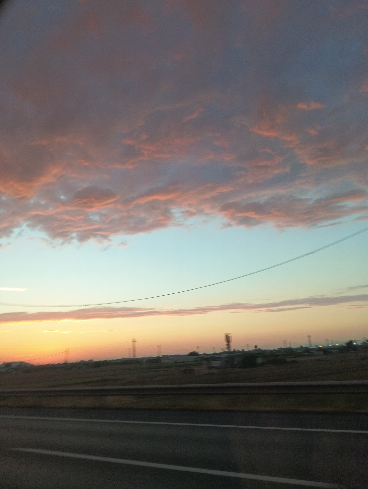 Highway drive at sunset, city skyline in the distance