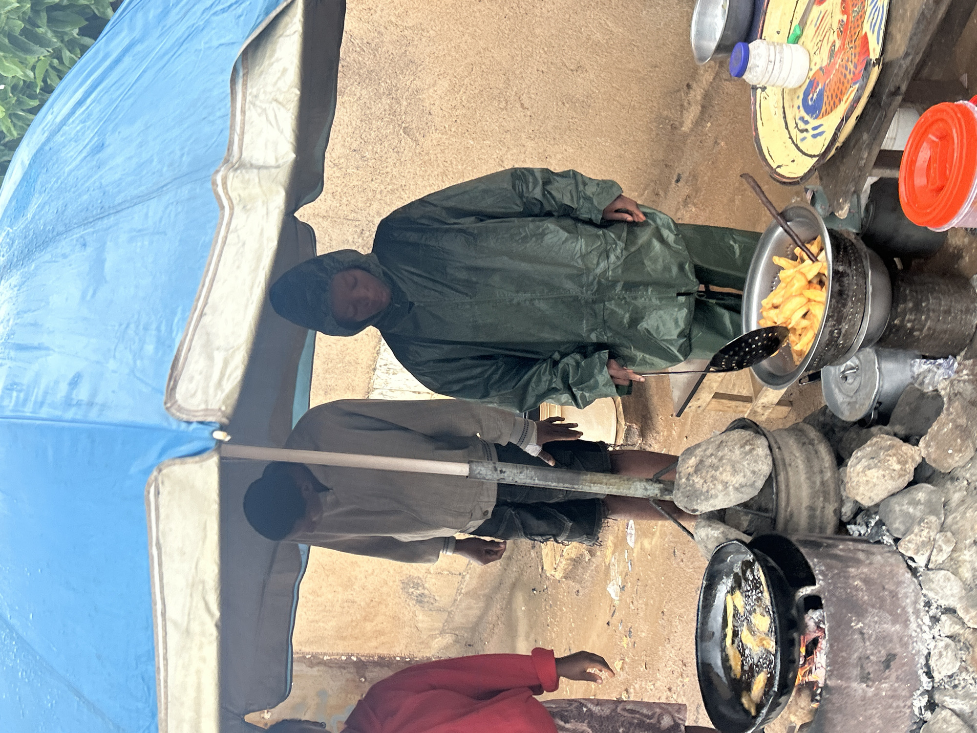 Street food vendors serve customers under tarps in Jos