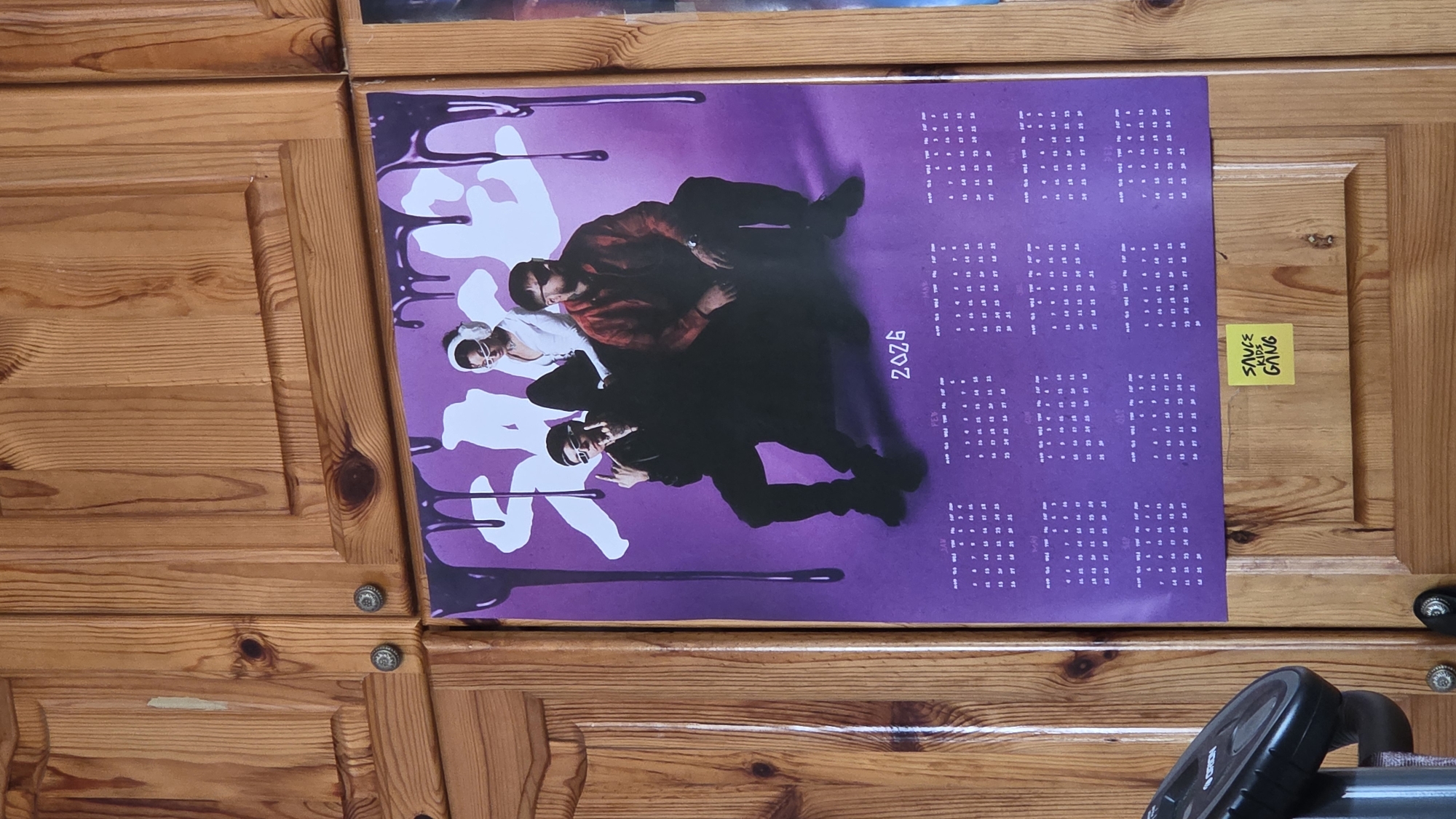 Purple poster with stacked figures spotted on wooden cabinet