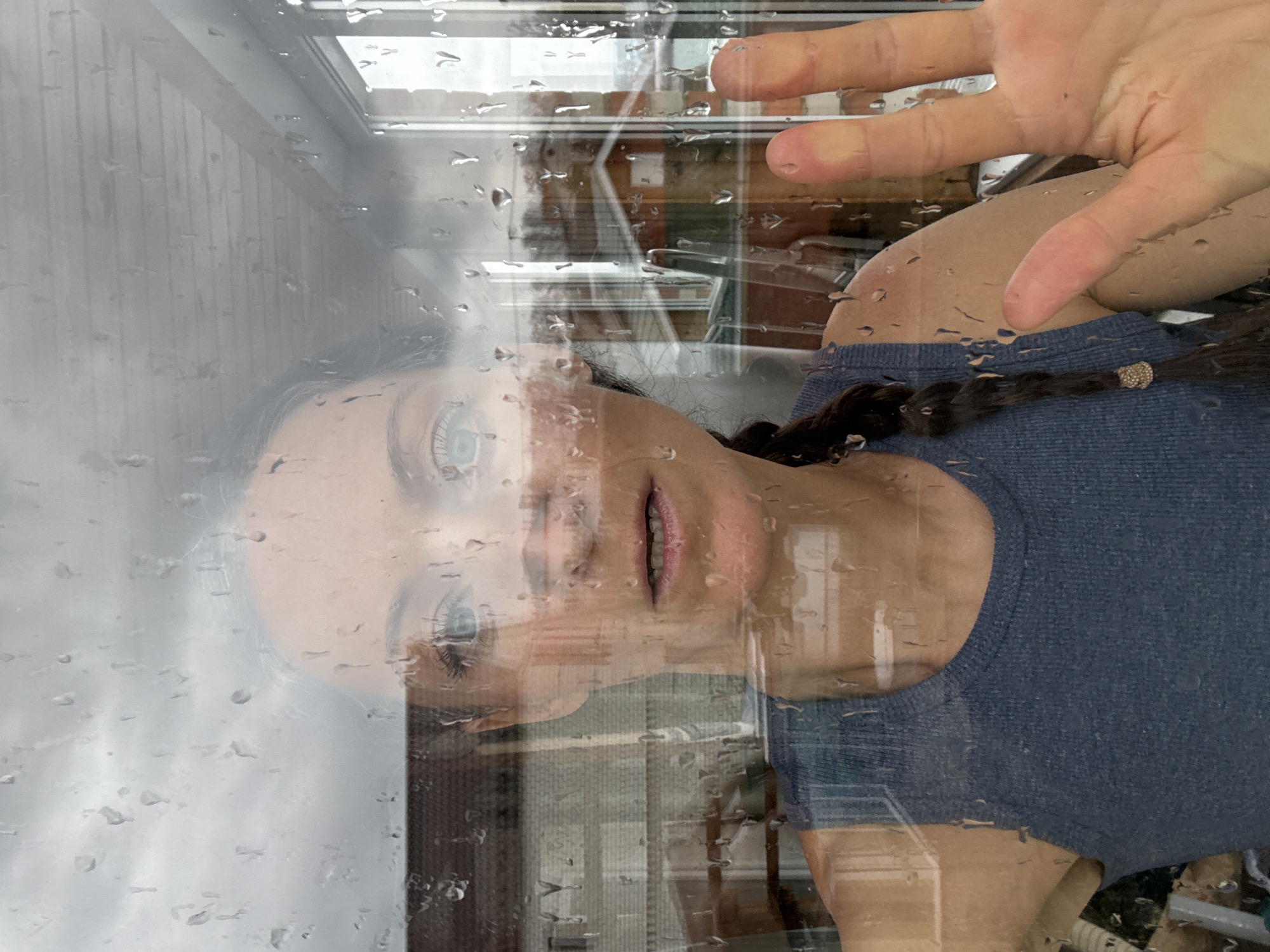 Woman observed through rain-streaked window in Ulyanovsk morning