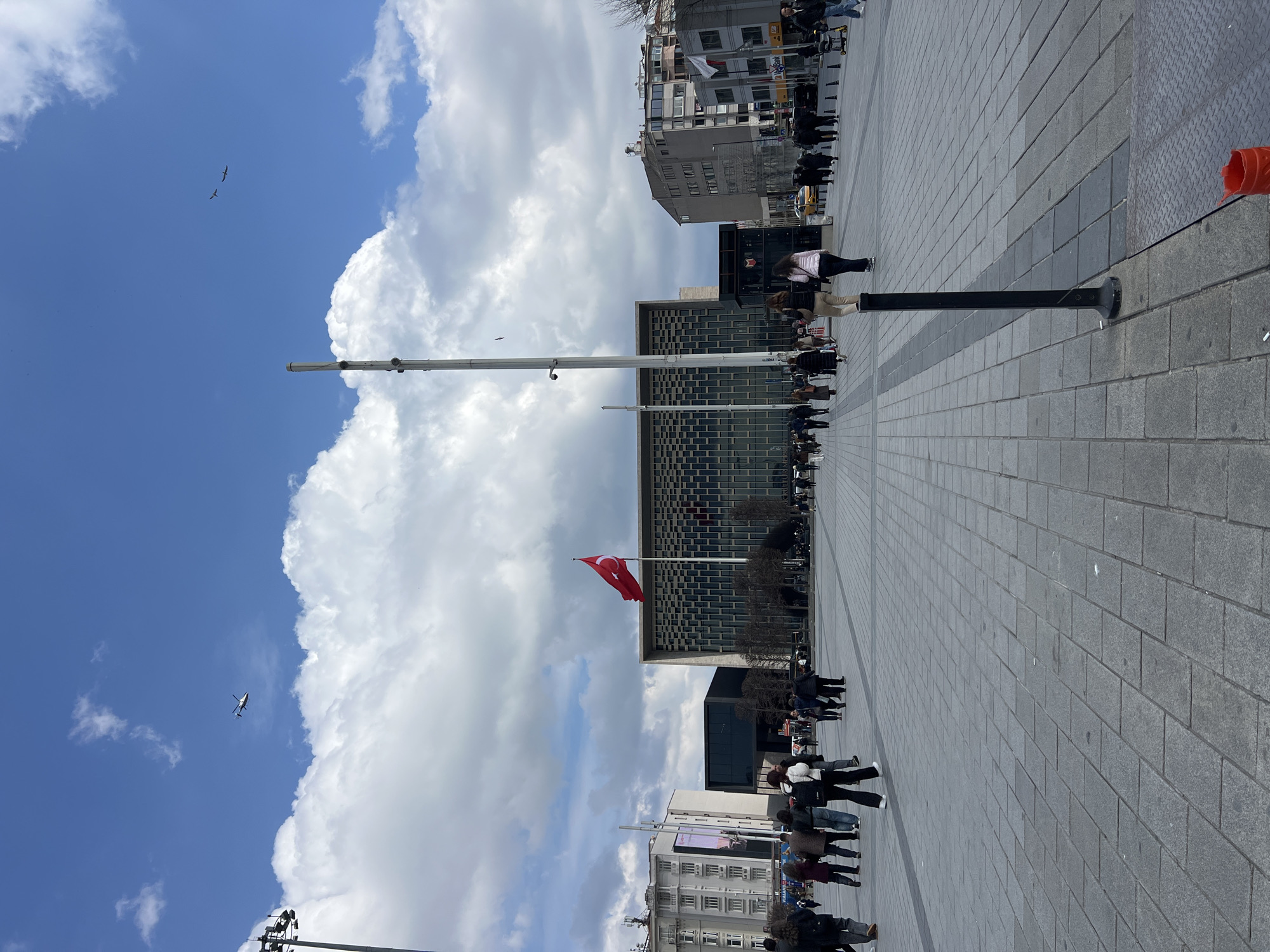 Pedestrians gather in Beyoğlu plaza near Turkish flag display