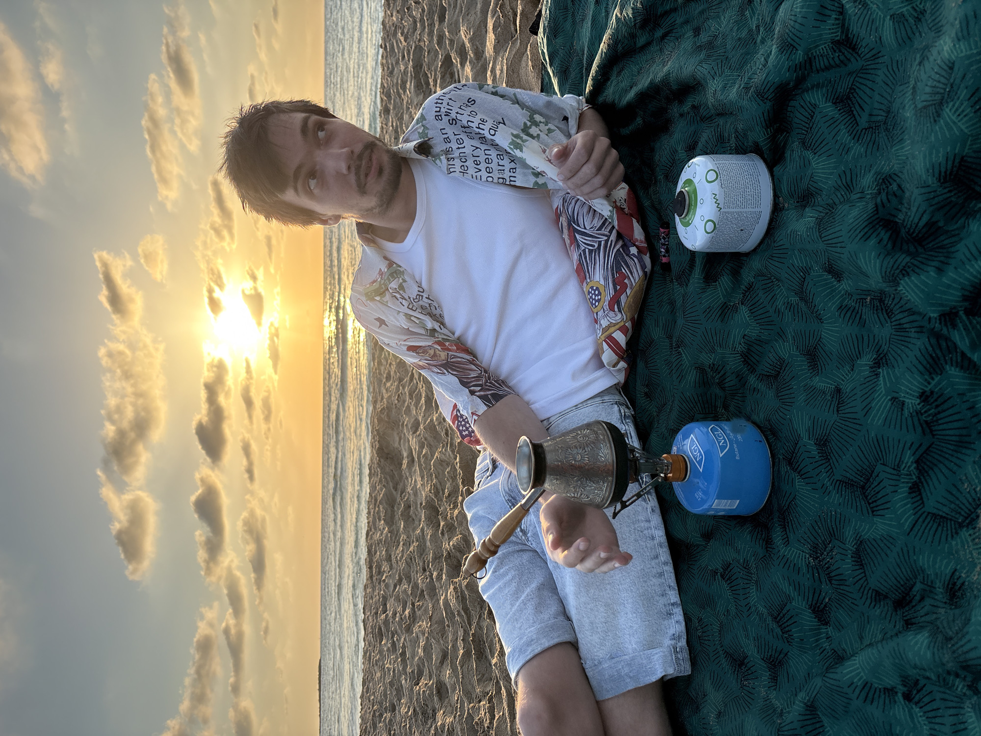 Beachgoer camps with portable stove at Israeli coast sunset