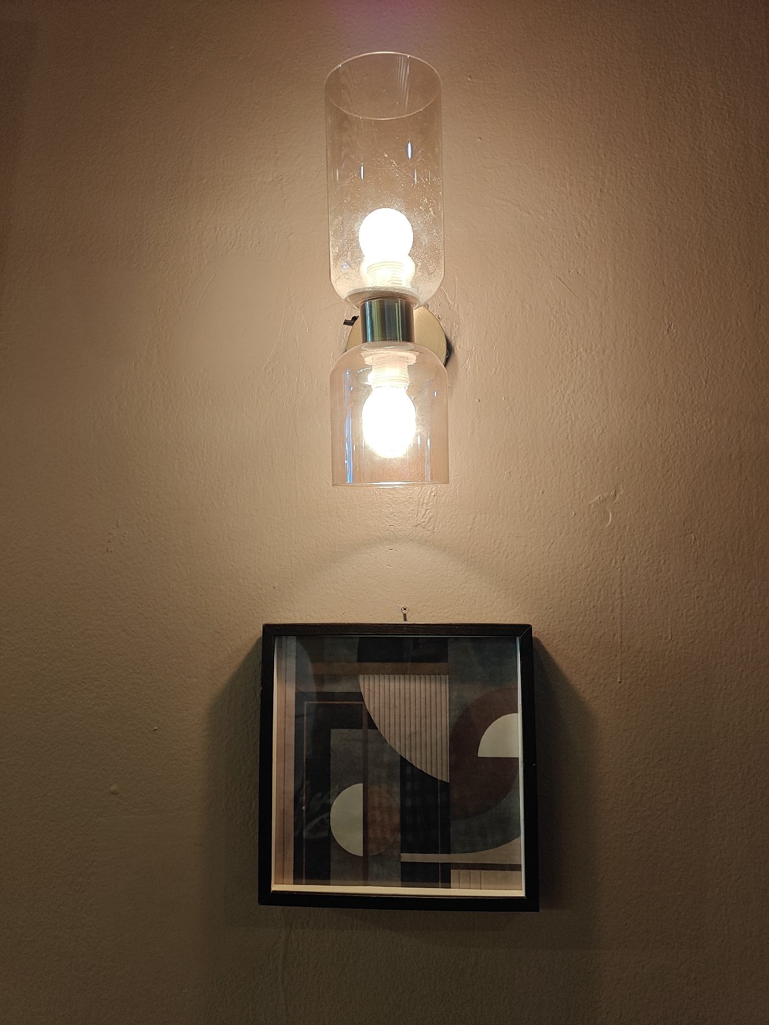 Modern dual-cylinder light fixture observed above artwork in Mumbai