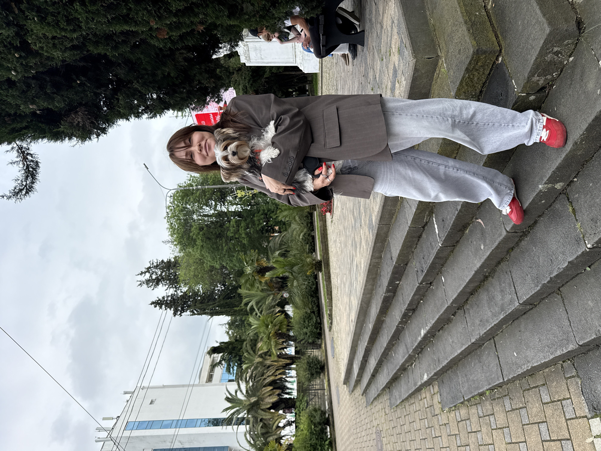 Woman walks small dog on Sochi sidewalk