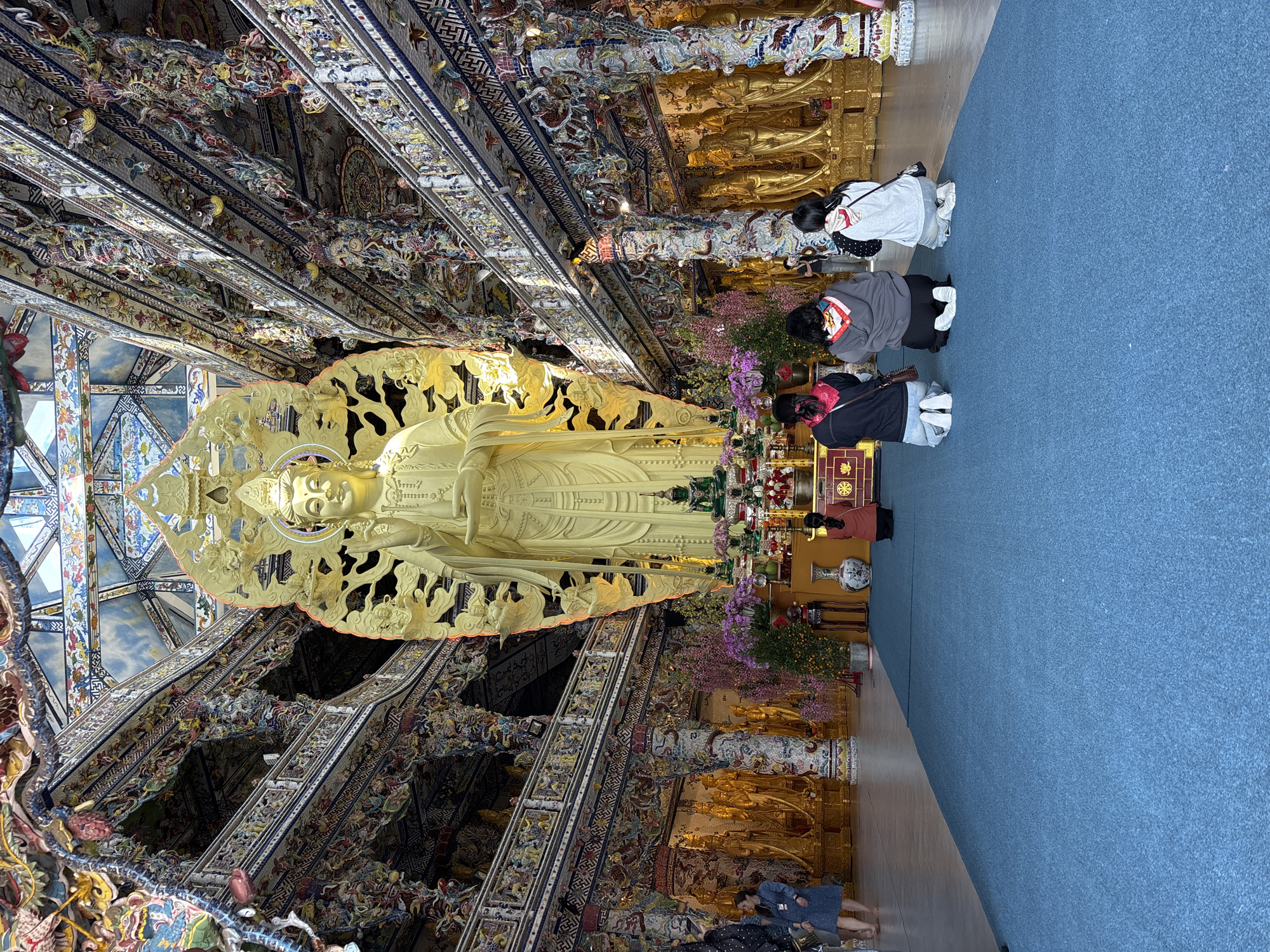 Worshippers pray at gold Buddha statue in Vietnamese temple