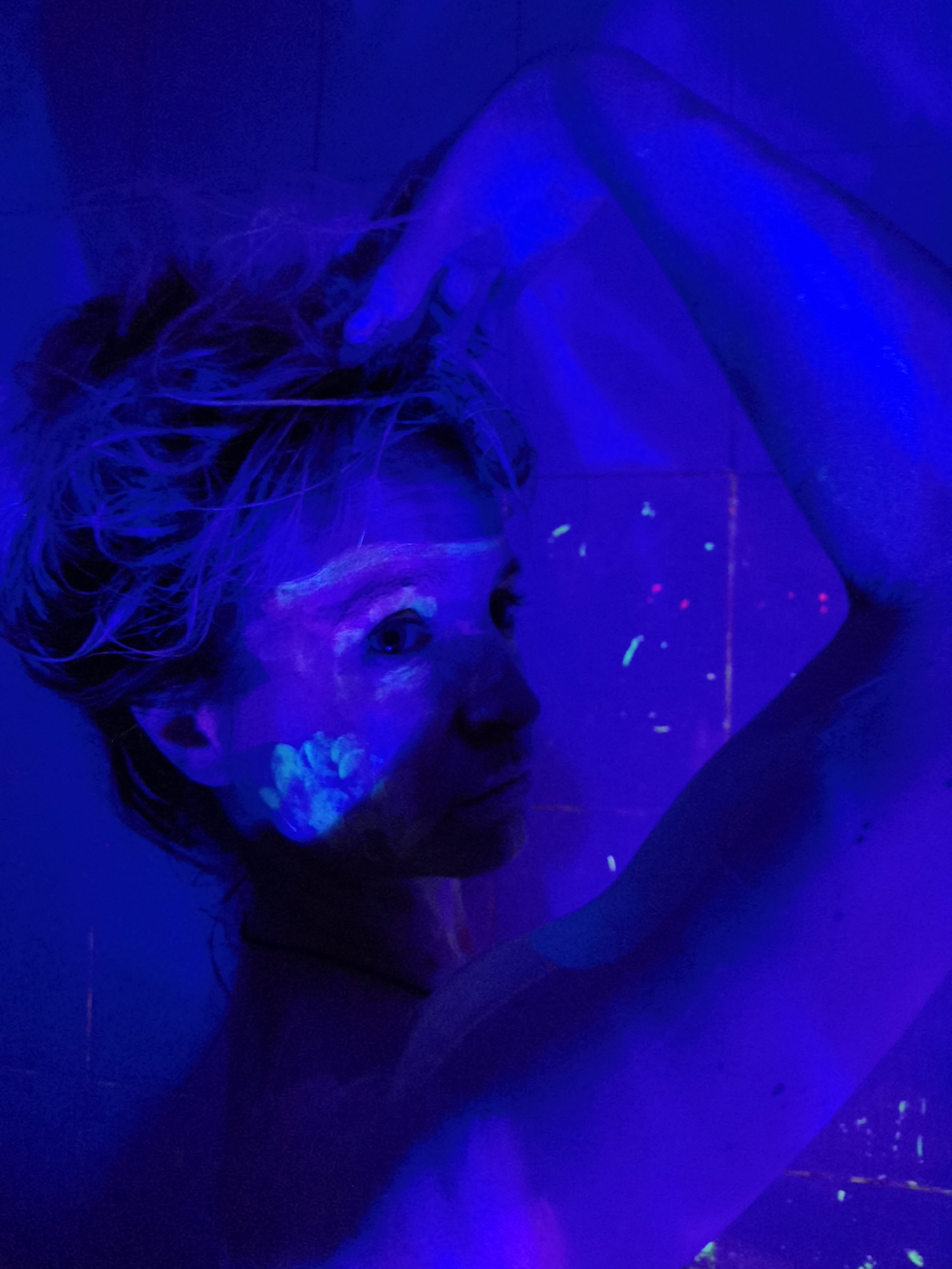 Person illuminated by UV light with glowing body paint