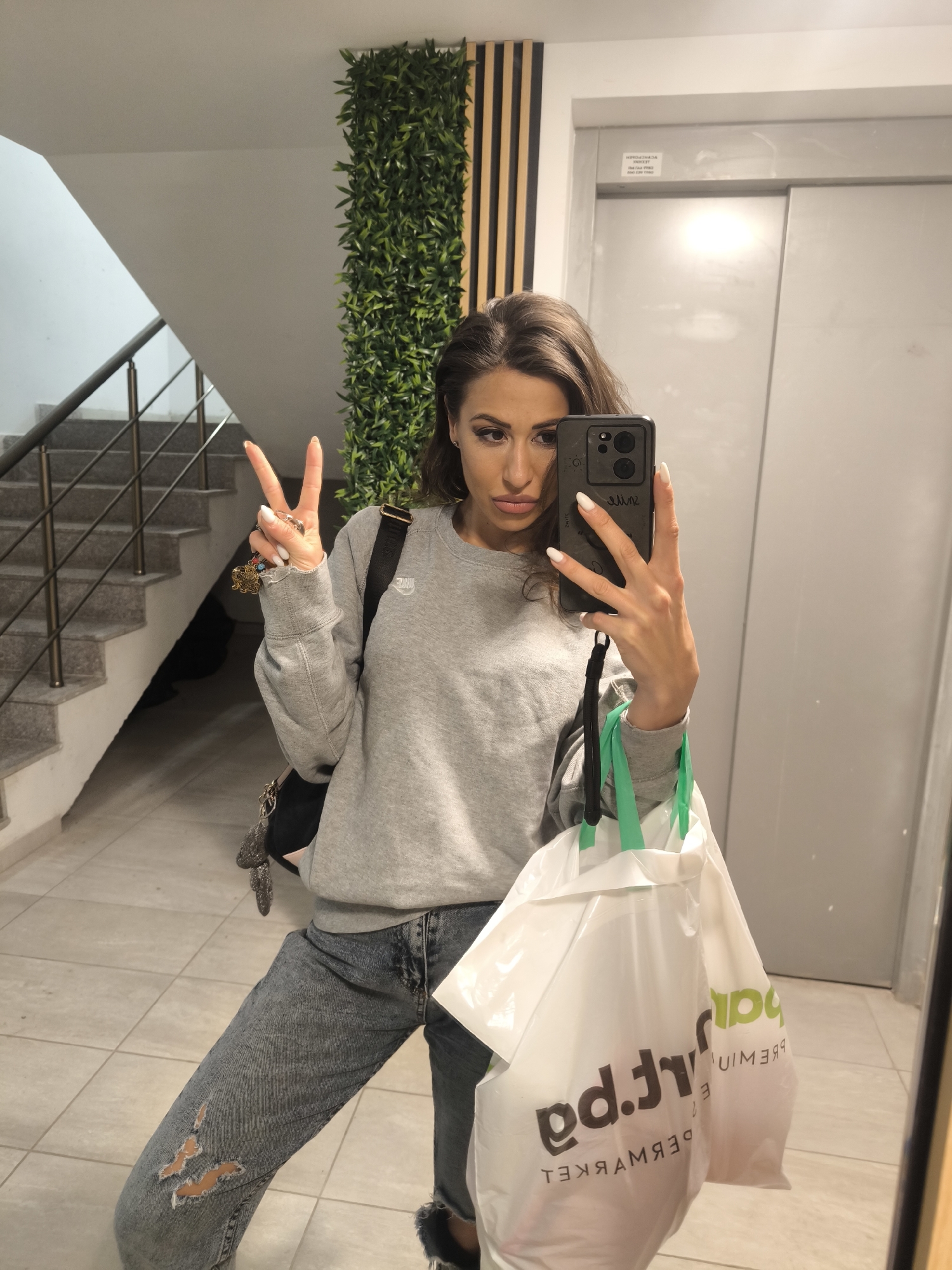 Woman with smartphone observed in apartment building hallway