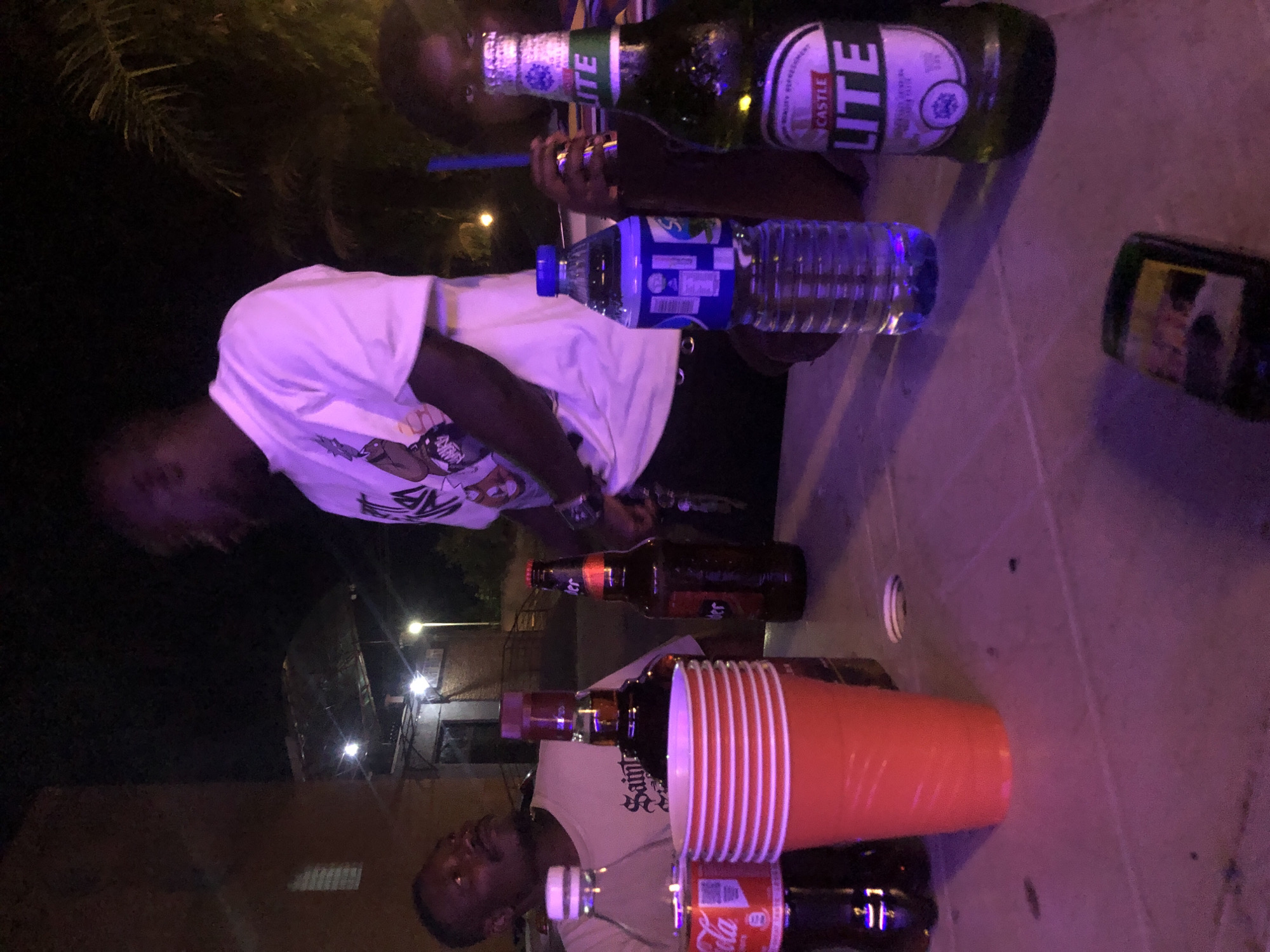 Friends gather for nighttime drinks outdoors under colored lights