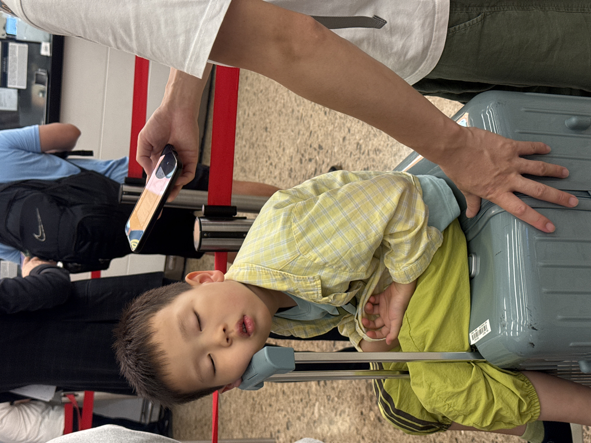 Catching sleep on a suitcase at a Hong Kong transit point