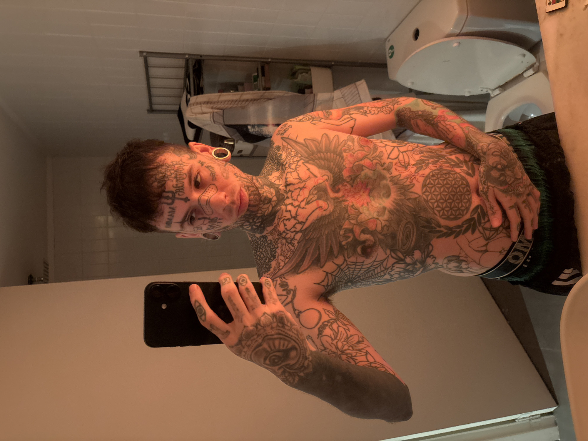 Tattooed man takes bathroom mirror selfie in Buenos Aires