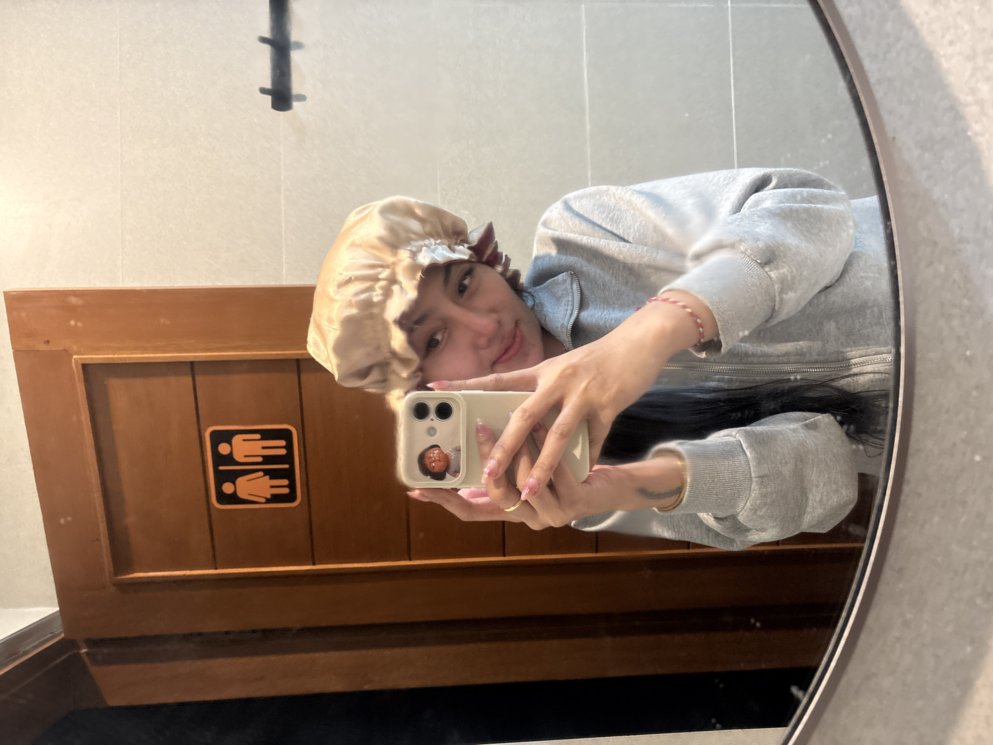 Person takes mirror selfie wearing bonnet and casual attire