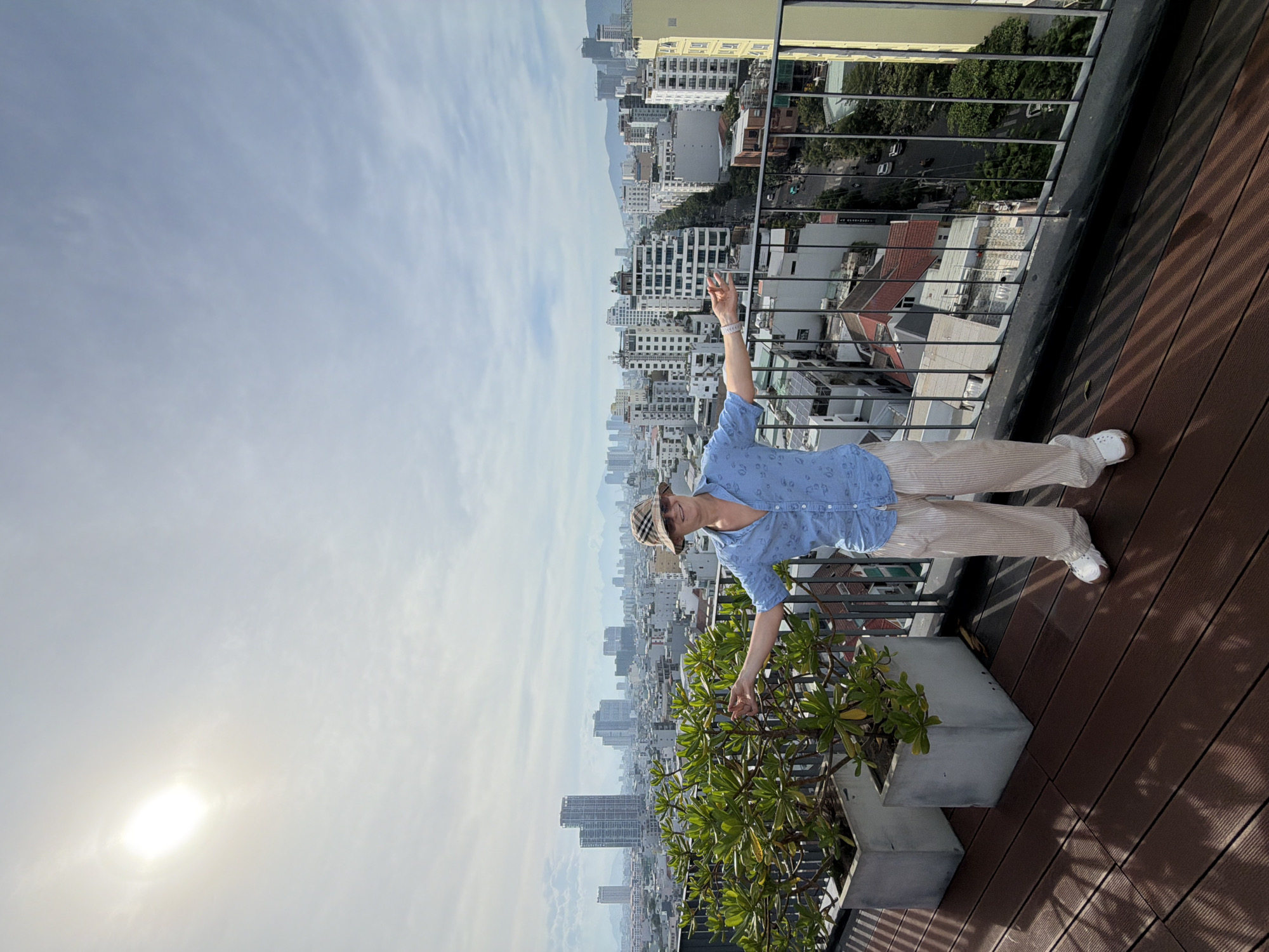 Man photographed on rooftop balcony overlooking Đà Nẵng cityscape