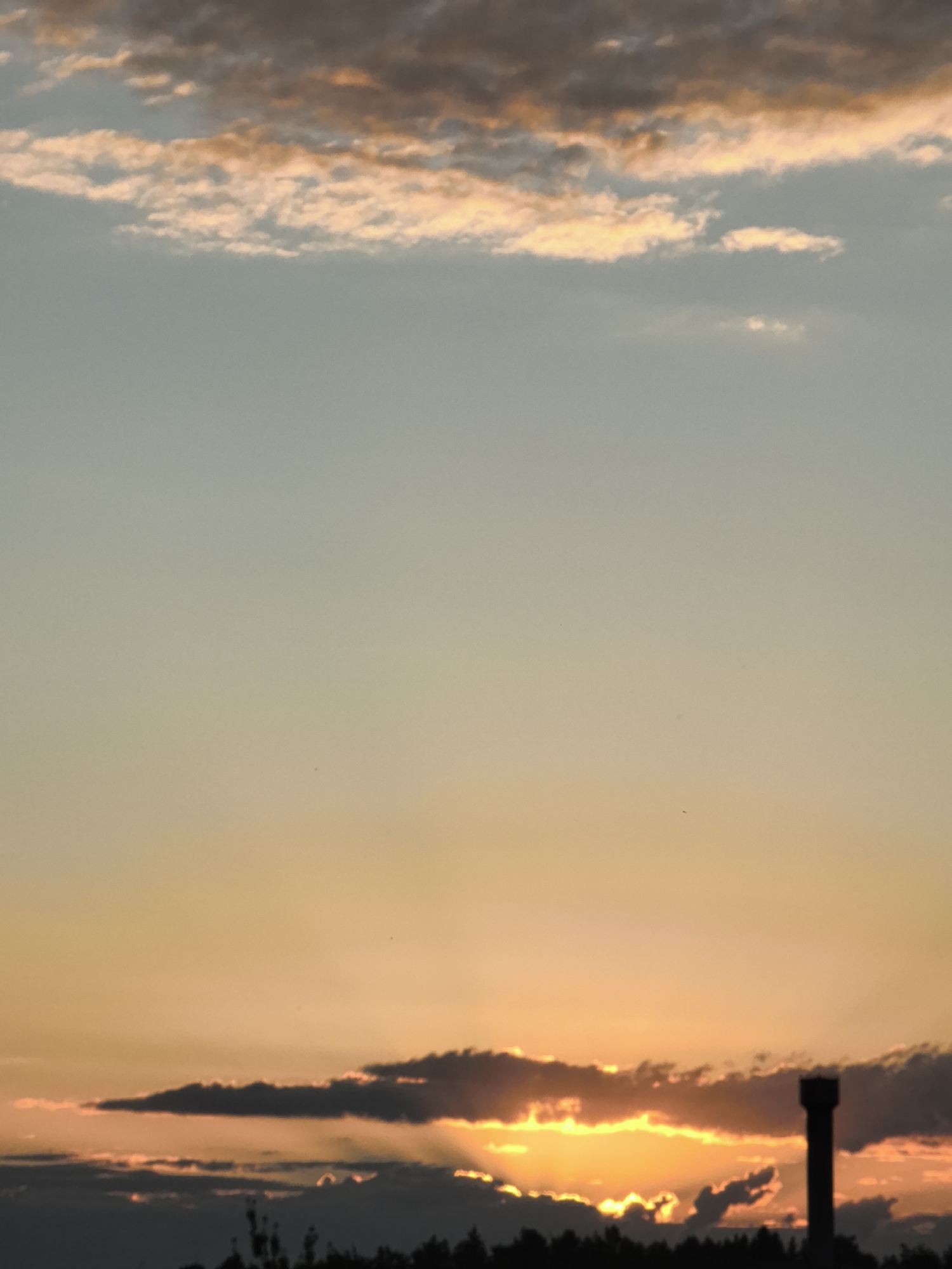 Water tower silhouetted against a vivid urban sunset