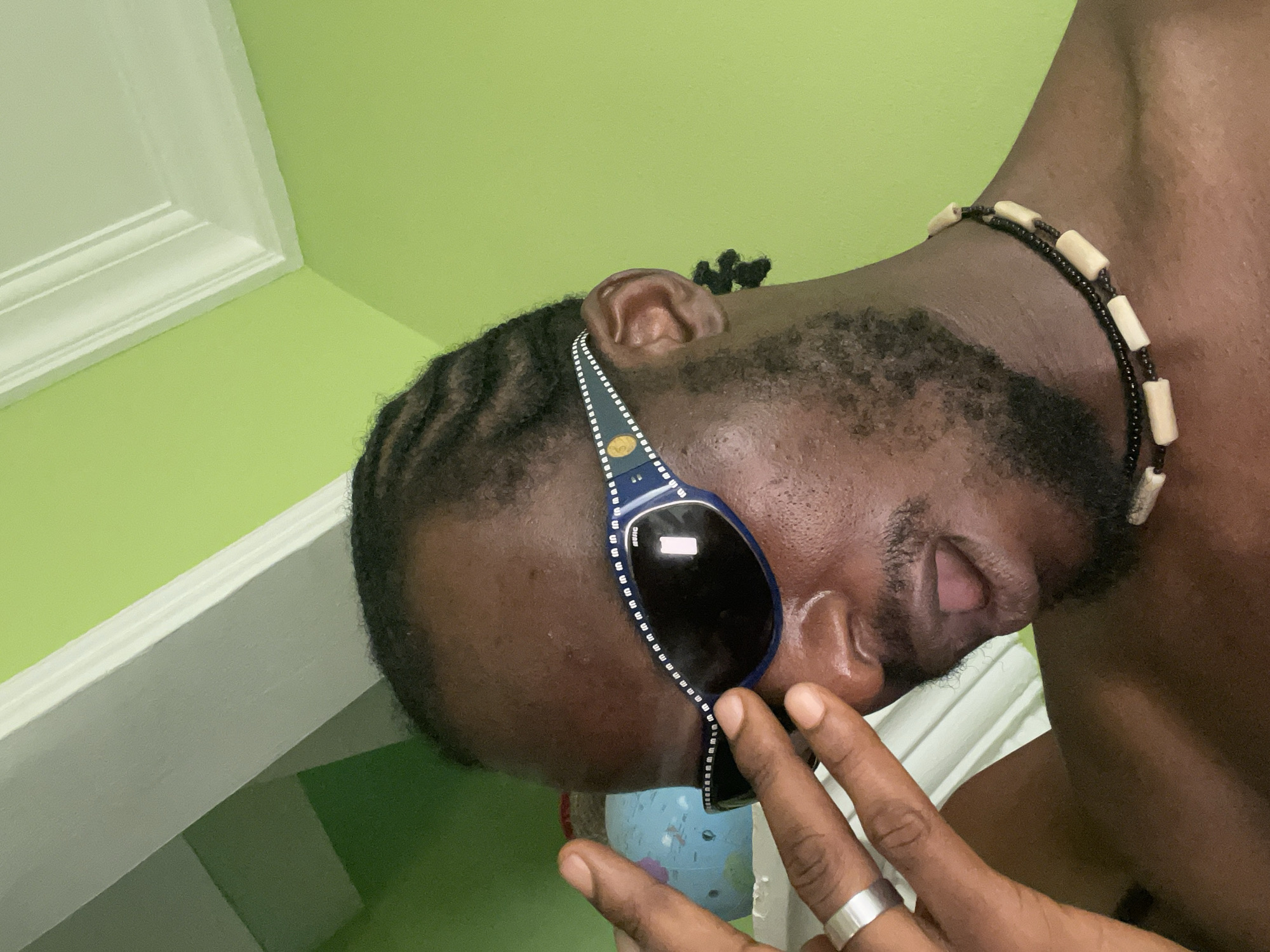 Person with sunglasses and beaded necklace captured indoors
