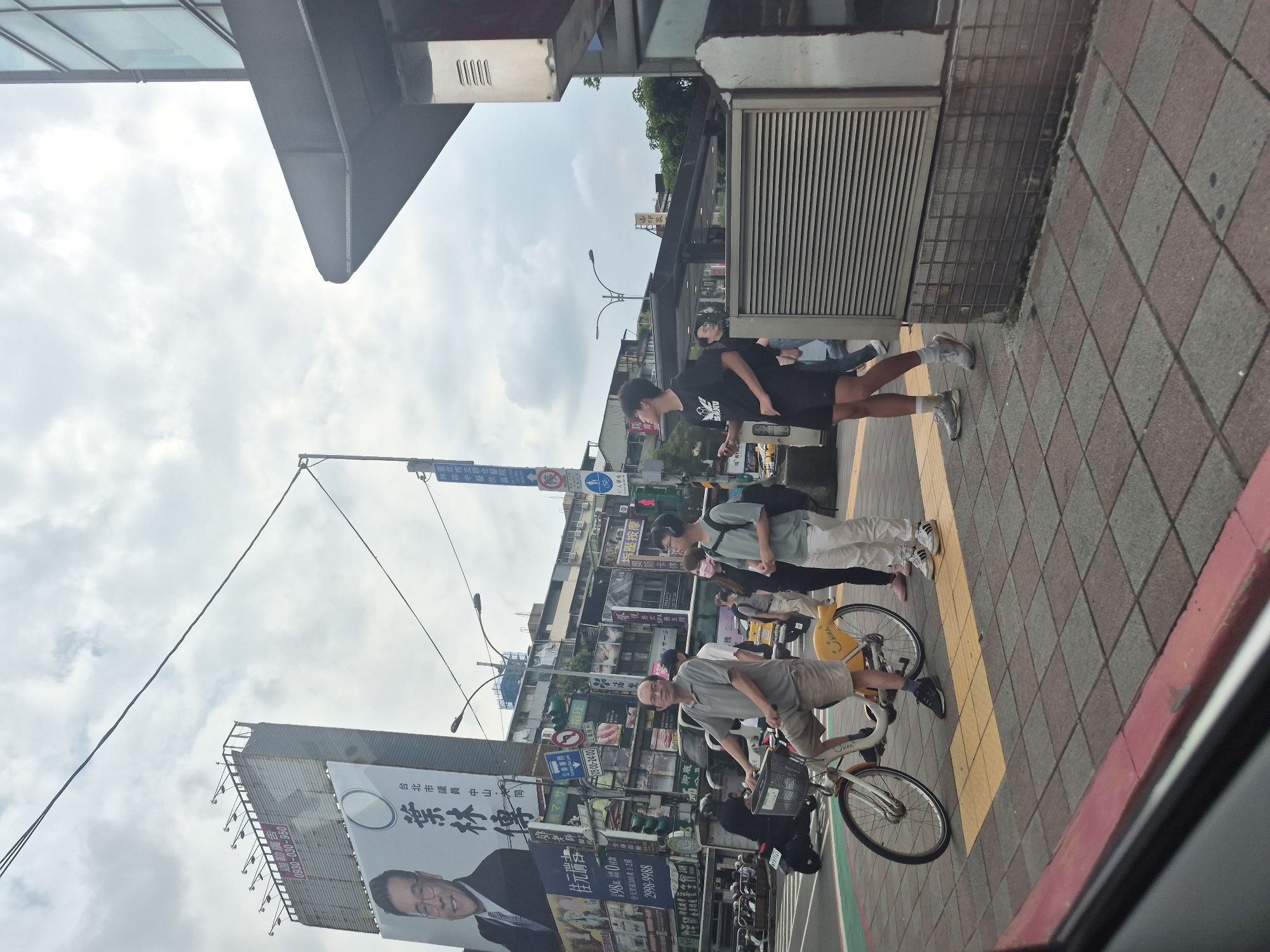 Street-level intersection scene near a glass office tower in Taipei