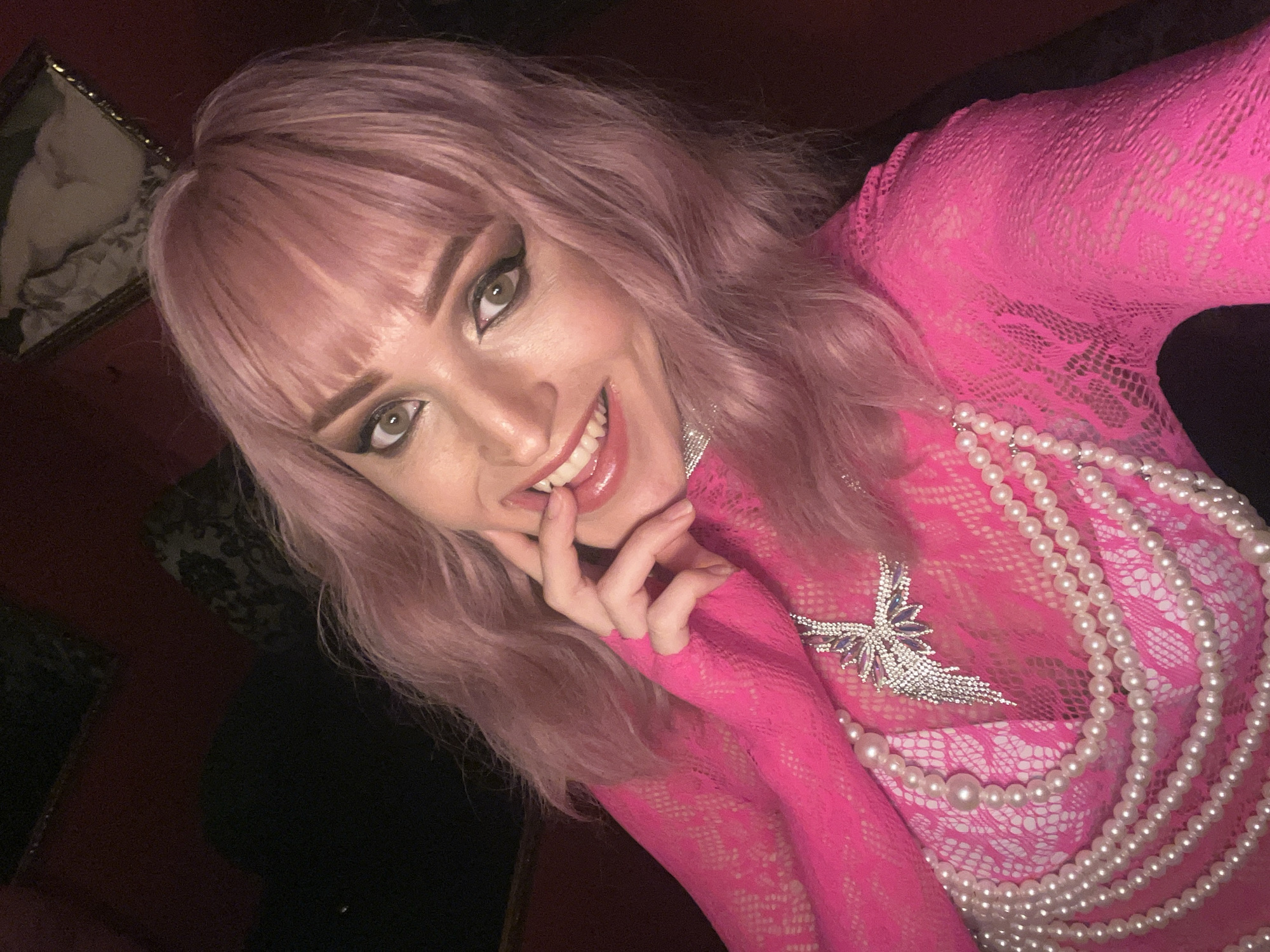 Pink-haired person photographed in selfies wearing bright pink outfit