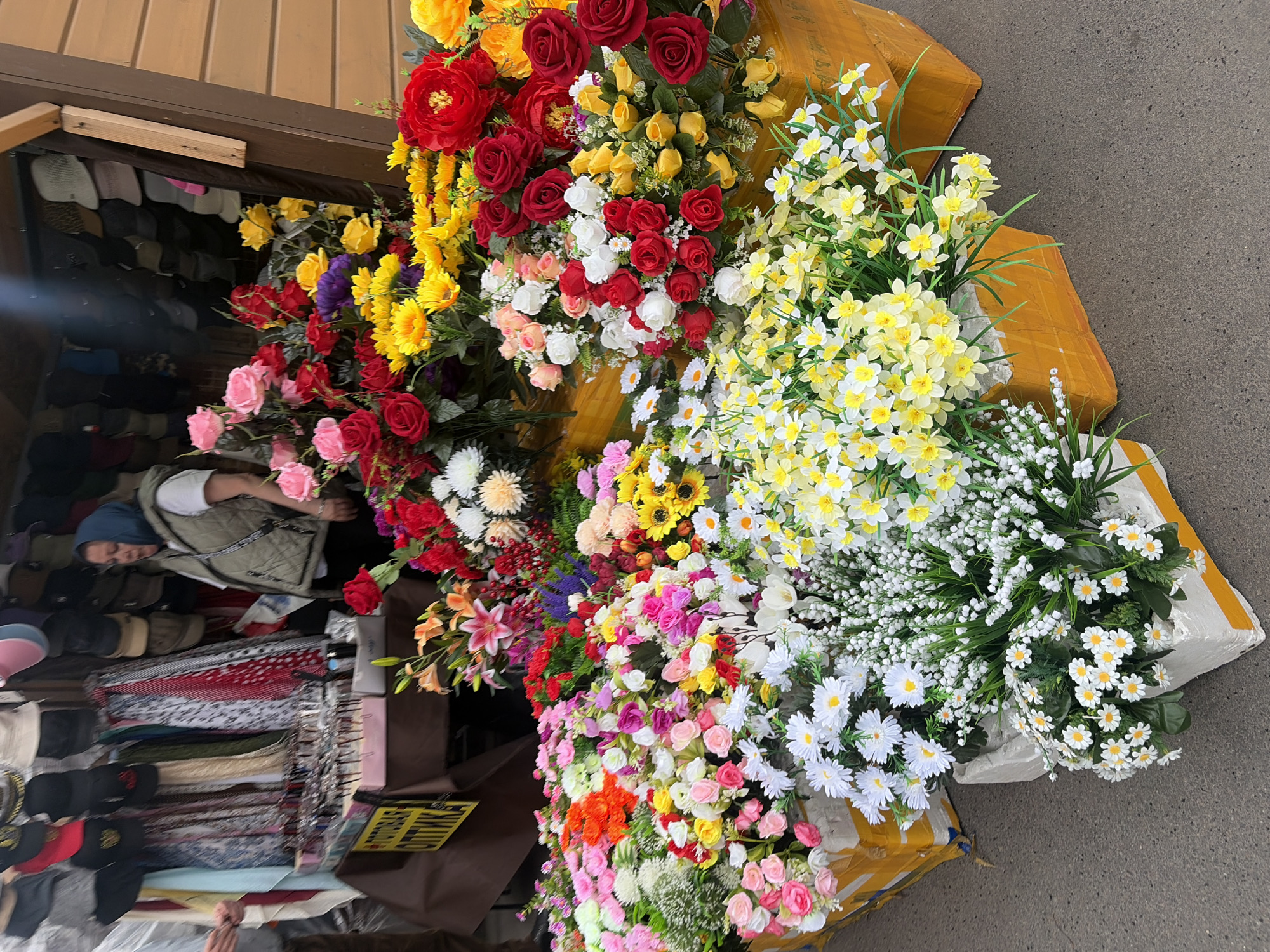 Street vendor sells flowers, accessories at Shushary market