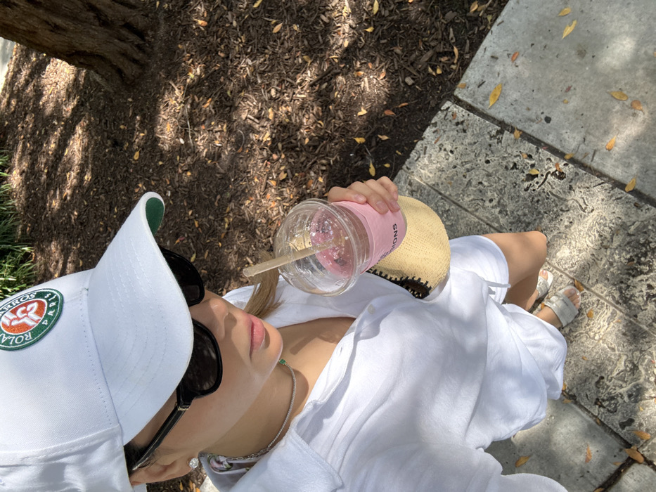 Person in white photographed with drink on Miami Beach