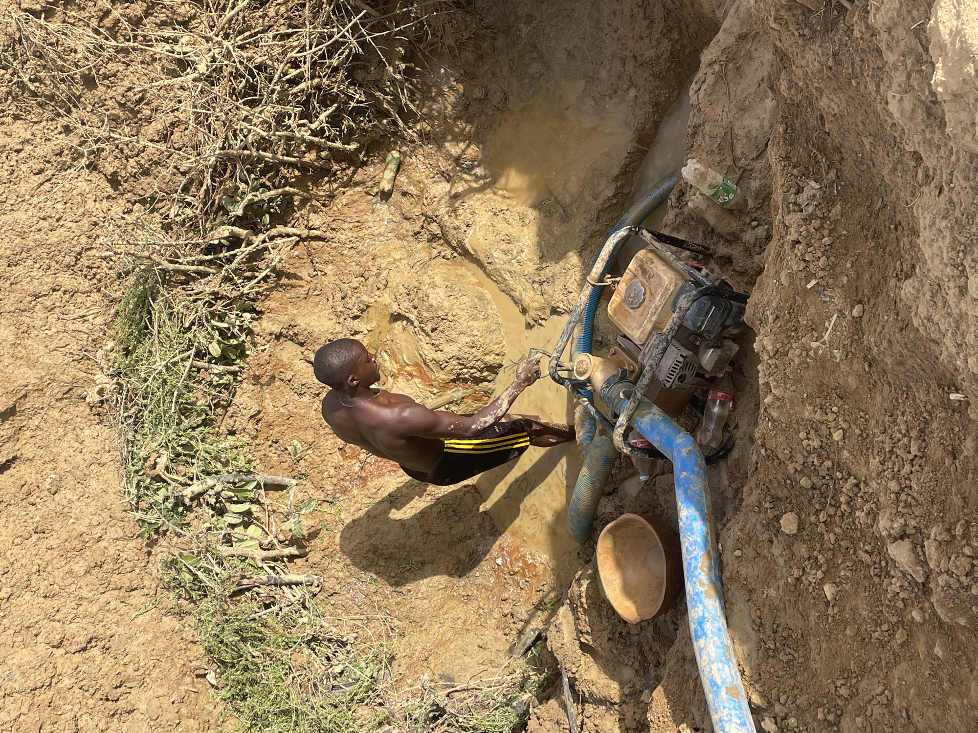Man works at muddy water pit in Gana Daji