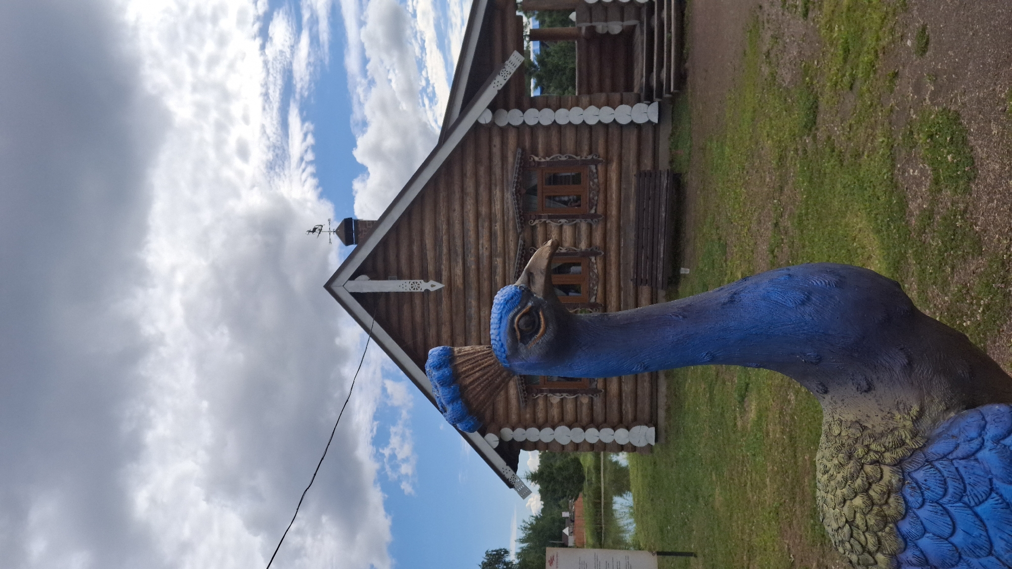 Rustic log compound in Peterhof with folk carvings and free-roaming birds