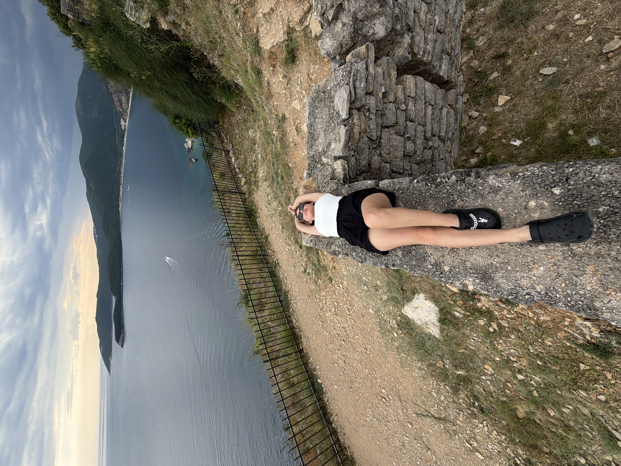 Person rests on stone structures near water in Prijevor