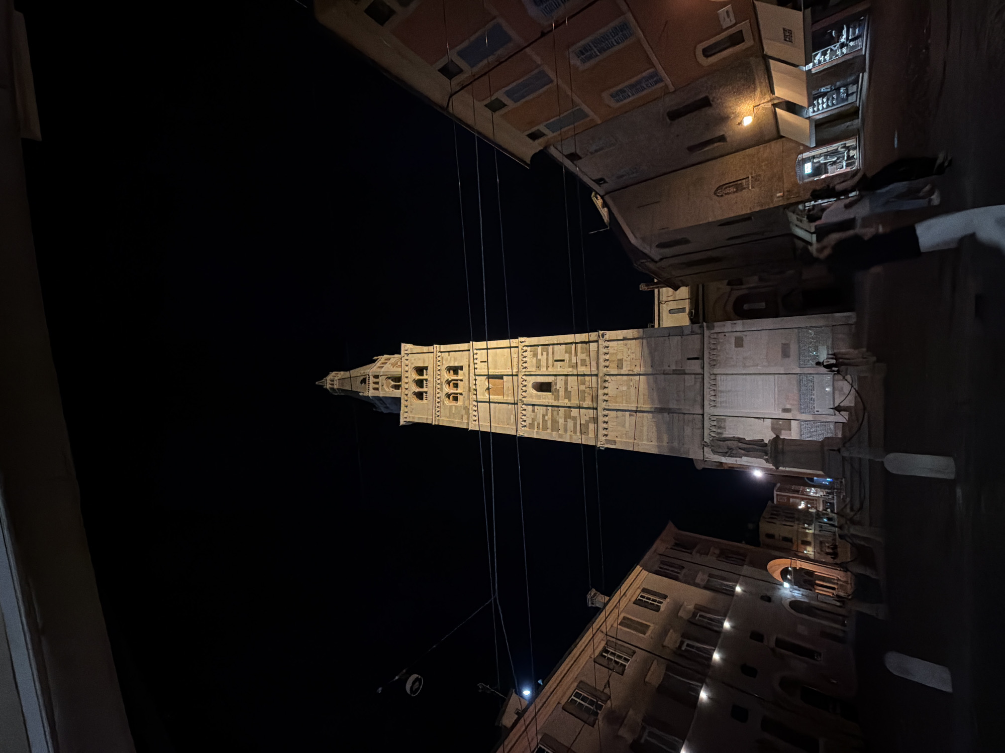 Modena's illuminated towers and umbrella-lined streets at night