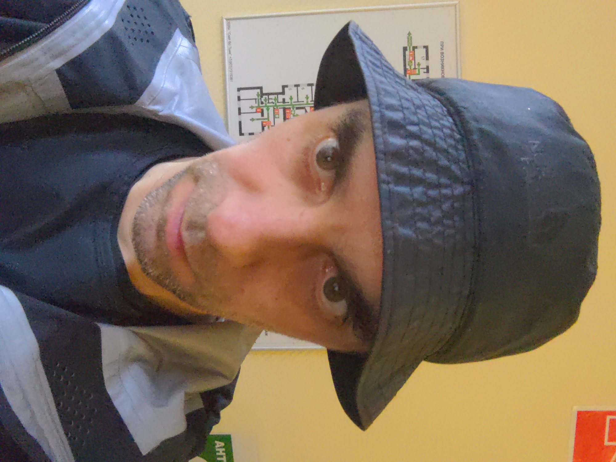 Man in bucket hat poses for selfie near schematic diagram