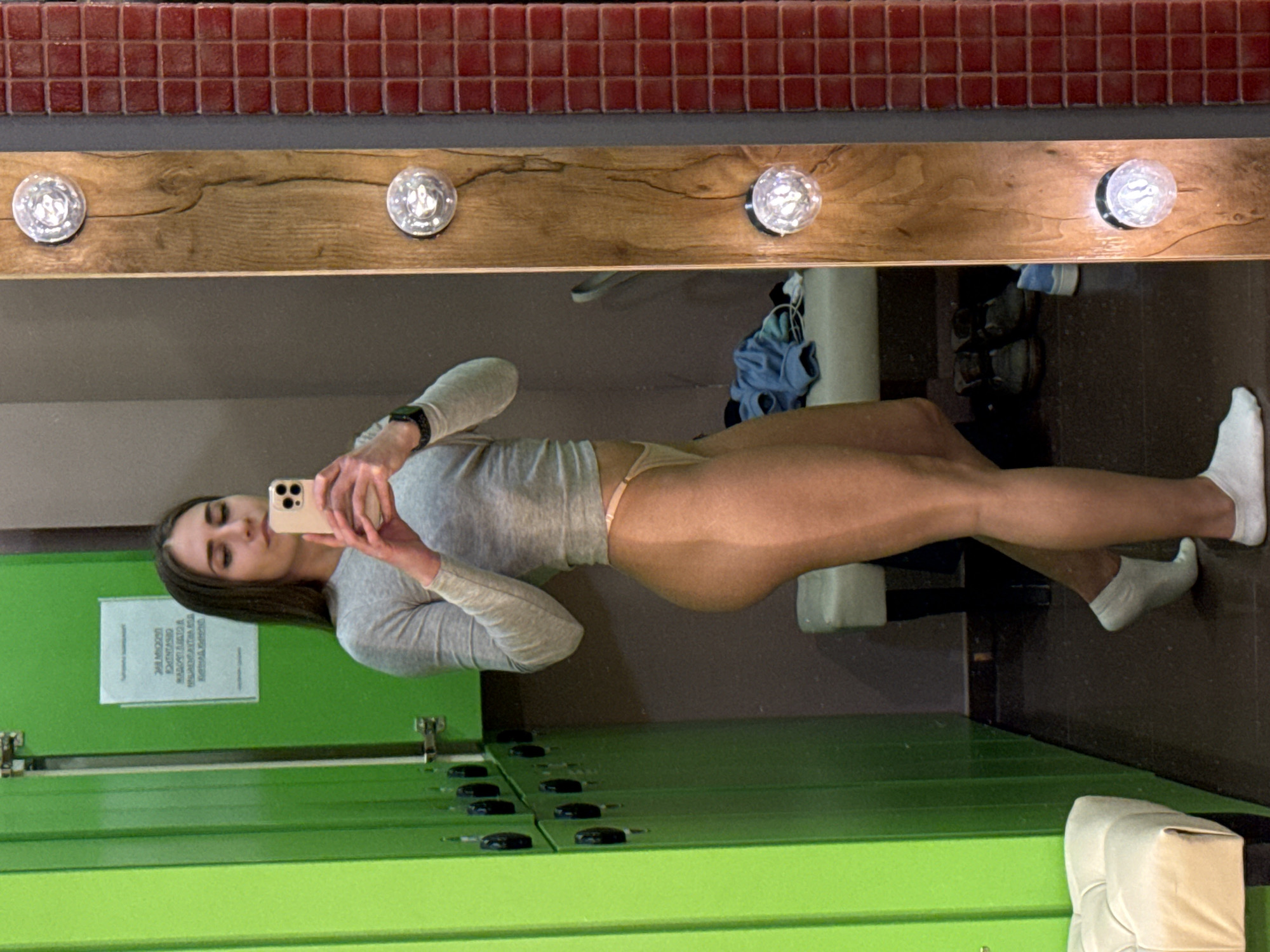 Woman takes mirror selfie in locker room area