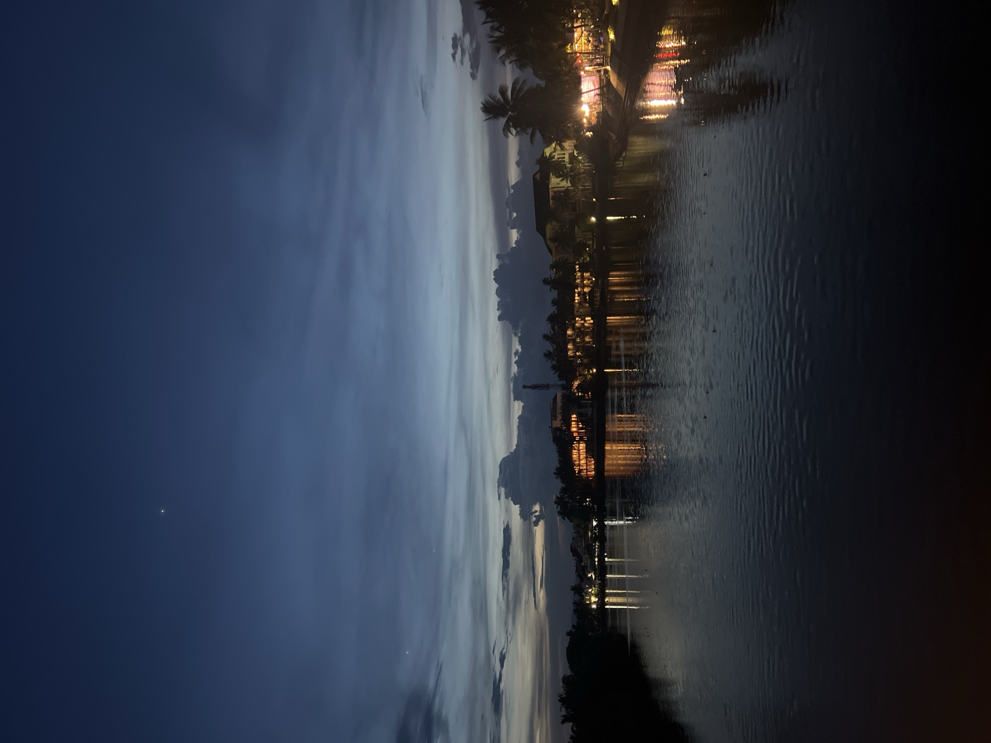 Hoi An riverfront at dusk: bridges, palms, and waterside lights