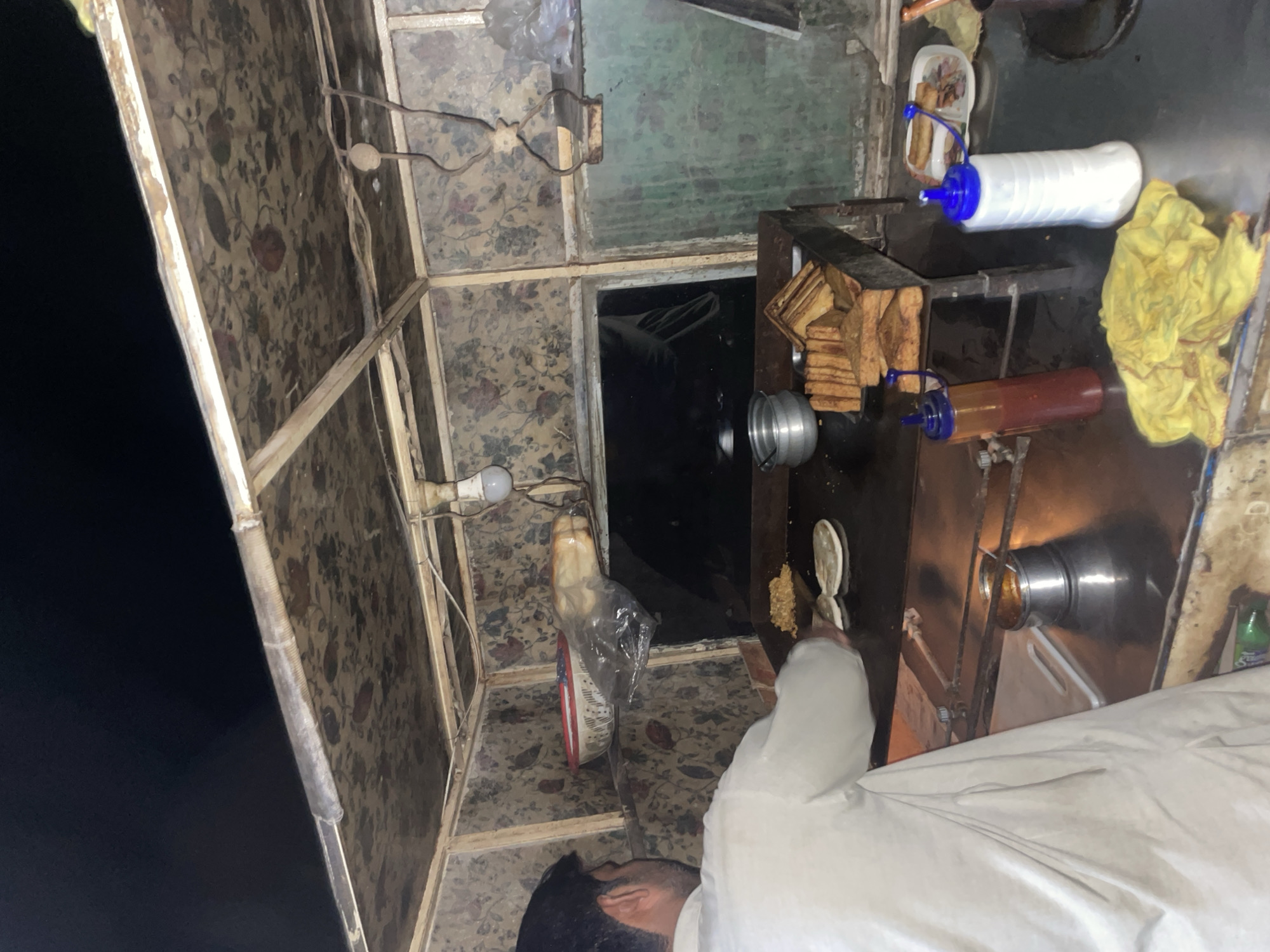 Food vendor serves customers at nighttime stall in Karamsar