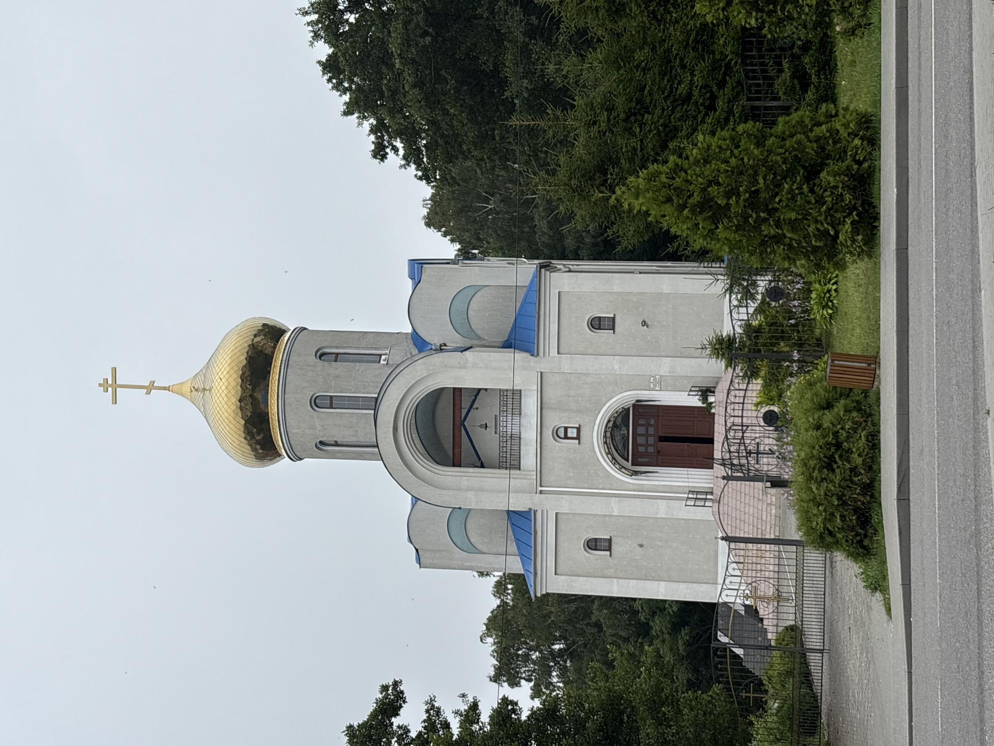 Orthodox church and a red Dodge Challenger in Pionersky, Russia