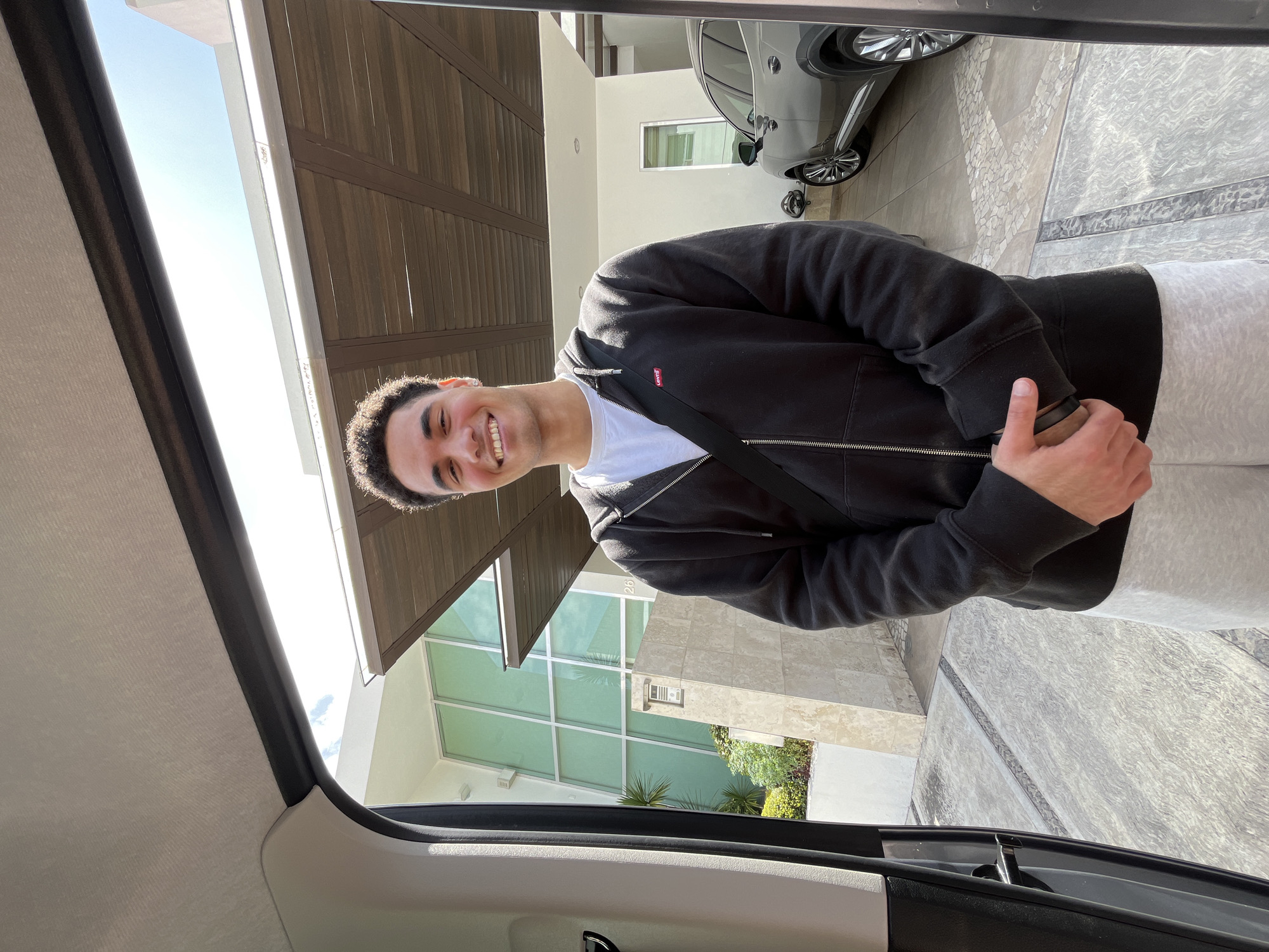 Man poses by house, vehicle trunk packed with supplies