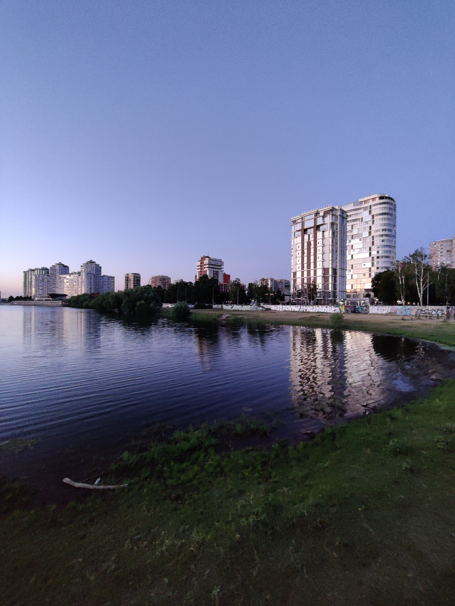 Krasnodar waterfront at dusk, modern towers lining the river