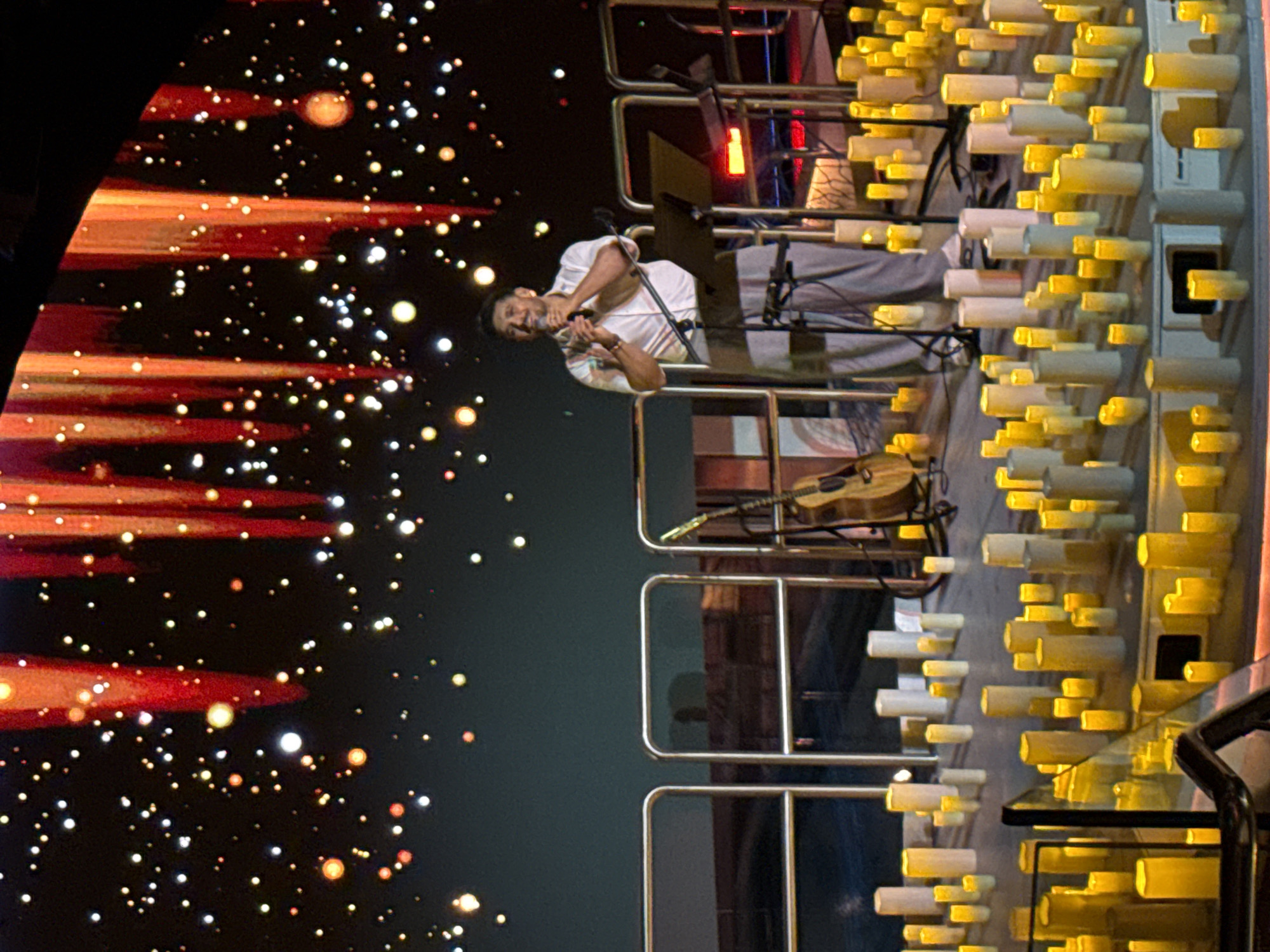 Male performer sings on stage in white shirt