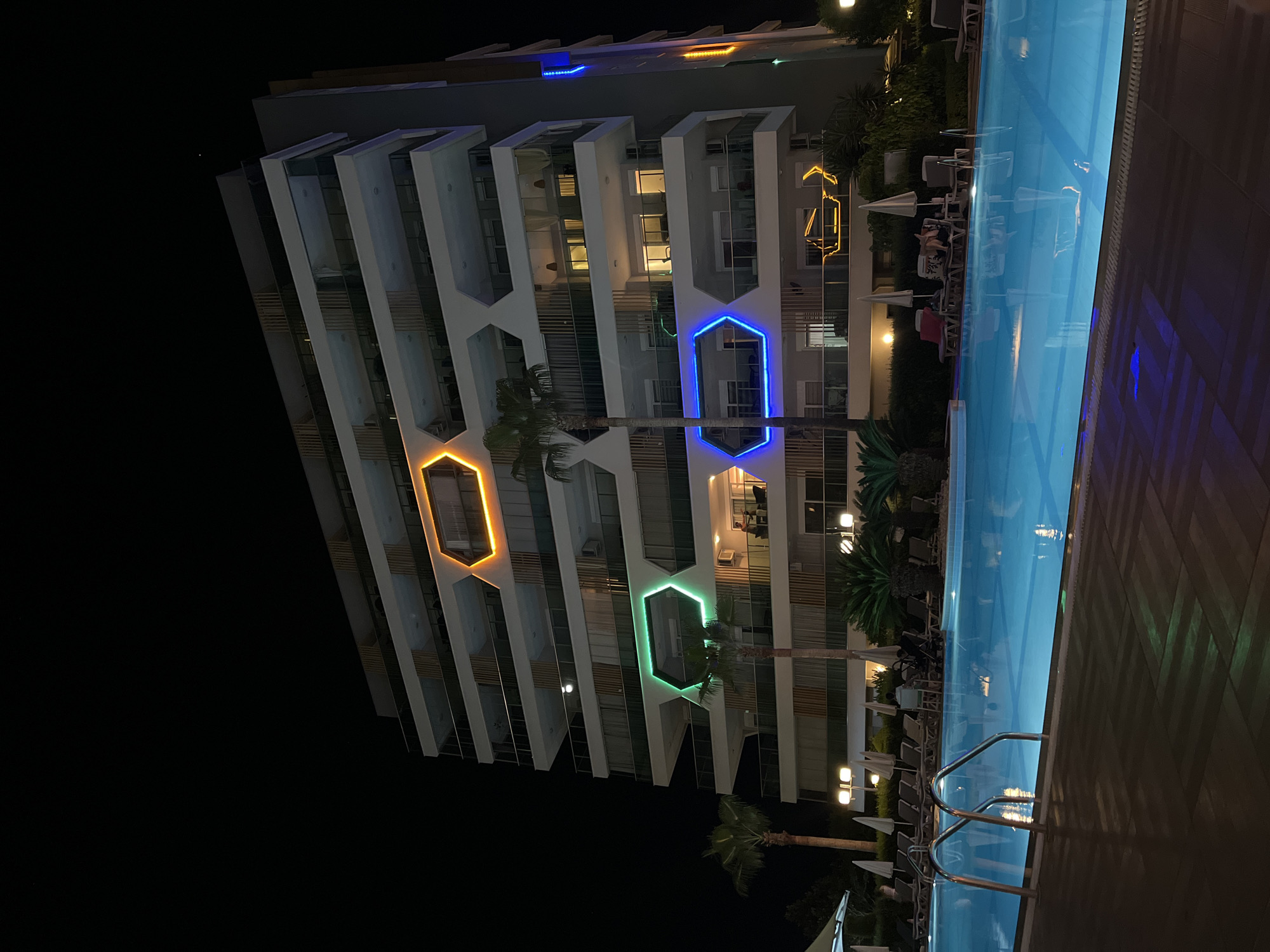 Alanya resort at night — pools, lit facades, and old stone steps