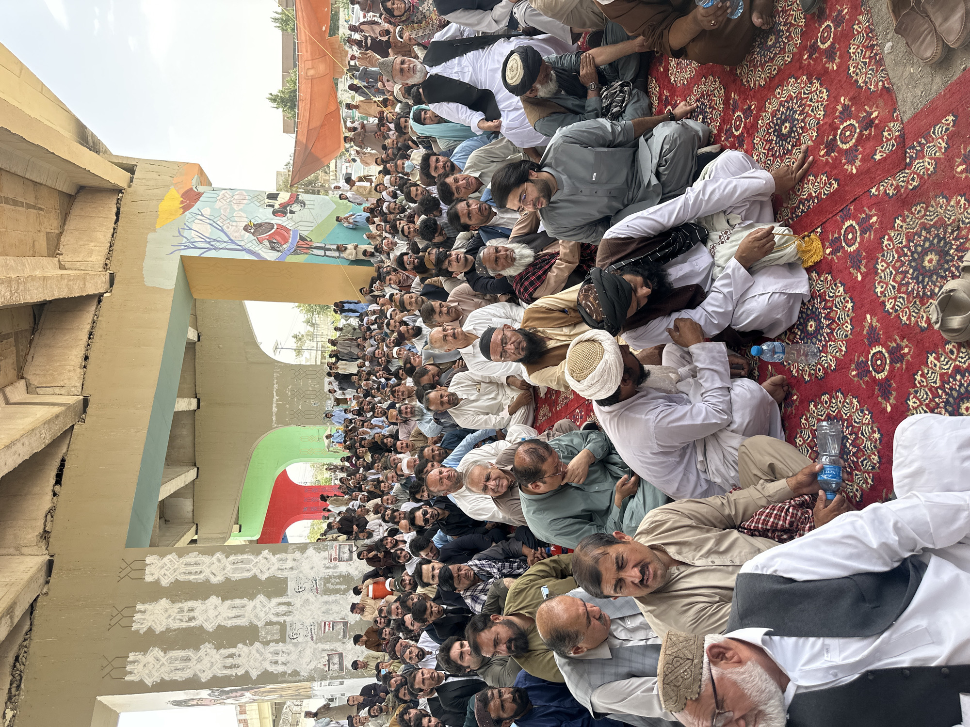 Large traditional outdoor gathering under overpass in Quetta